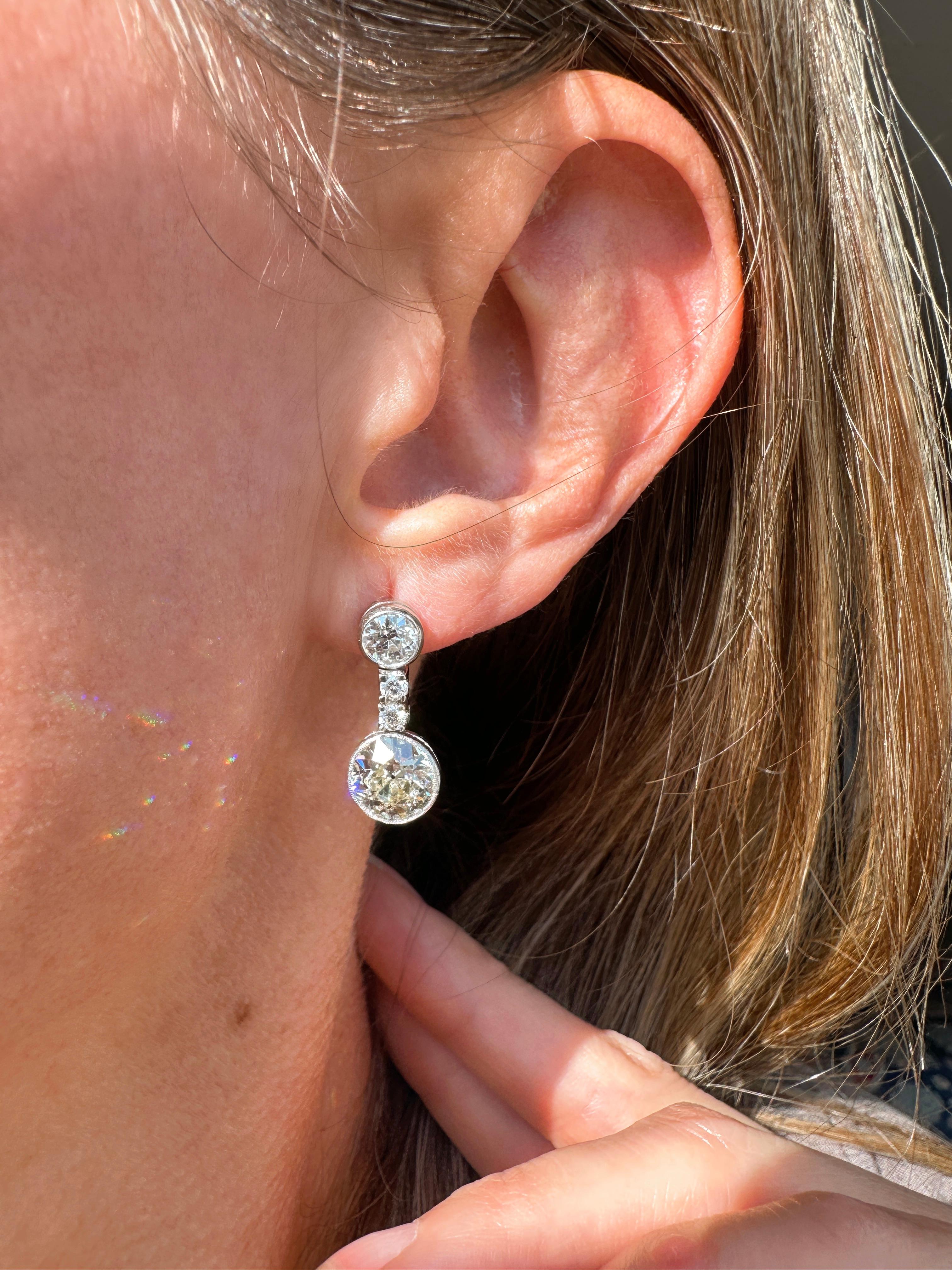 These dazzling Art Deco diamond drops highlight a sizable matched pair of sunshiny European-cut diamonds, together weighing 3.47 carats, swing and sway from below a.50 carat old mine-cut diamond post and pair of sparkling brilliant-cut diamonds.