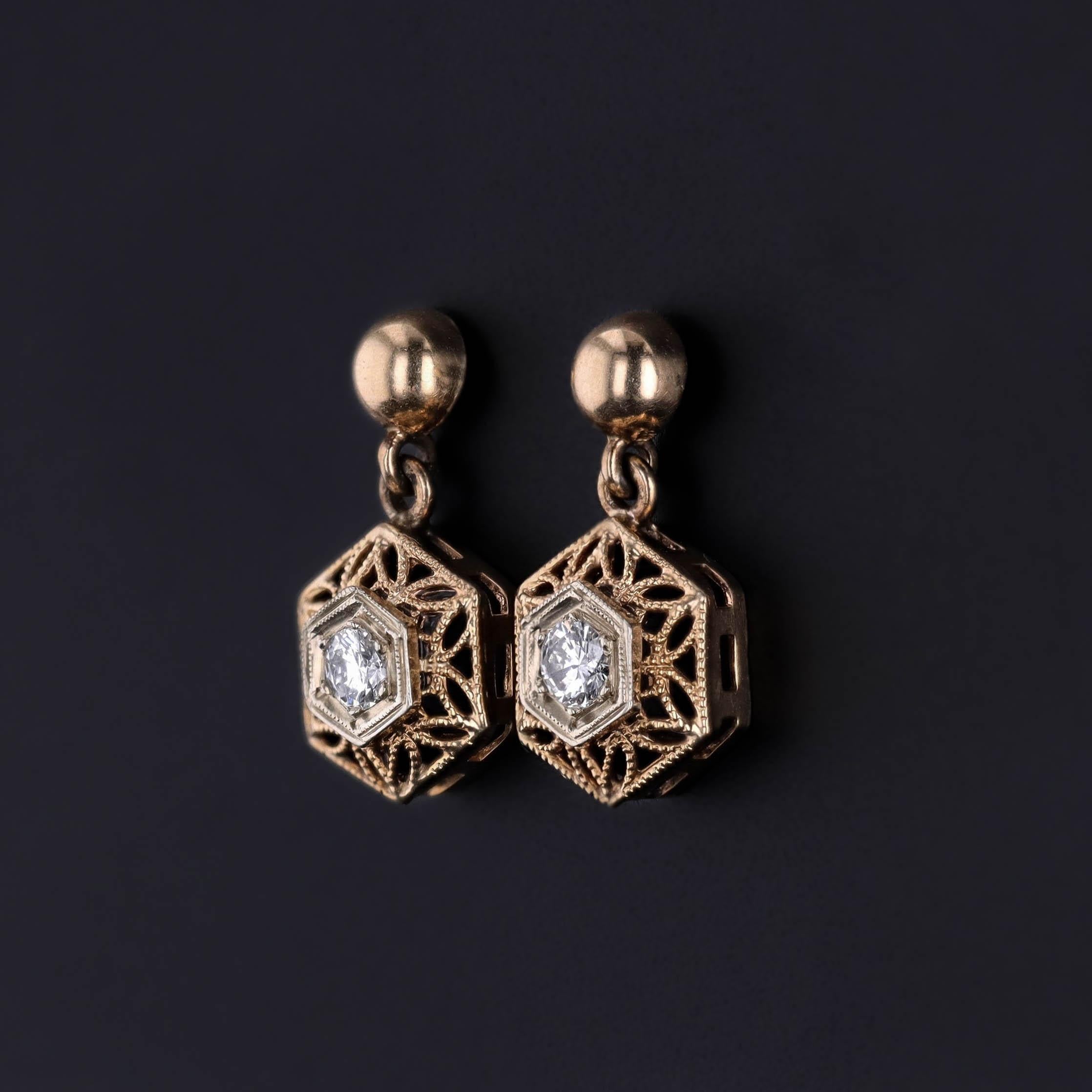 Expression intemporelle de l'élégance Art déco, cette paire de boucles d'oreilles (vers 1920-1930) présente des diamants brillants délicatement sertis dans un filigrane d'or jaune 12k avec des accents d'or blanc 14k. Le design ajouré reflète la