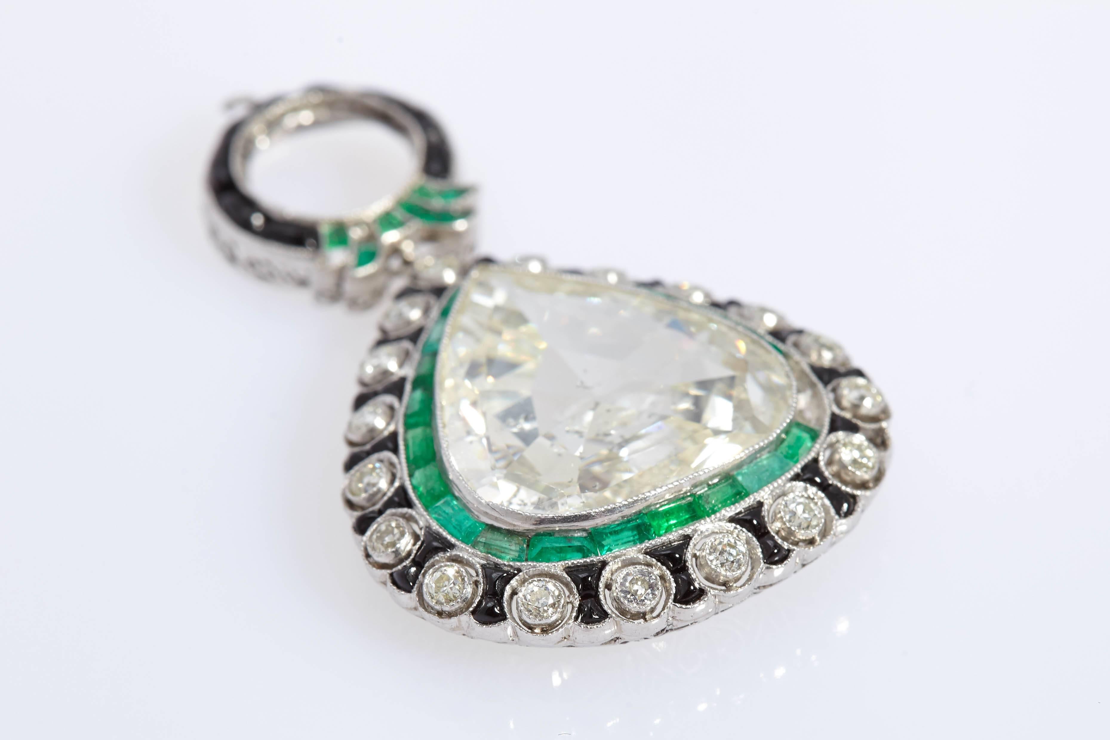 An Art Deco Pendant centering an impressive pear shape diamond (9.37 cts, K color, S12), the platinum mounting embellished with black enamel work and emeralds (two missing, to be replaced by us prior to final sale). Made in Italy, circa 1920.