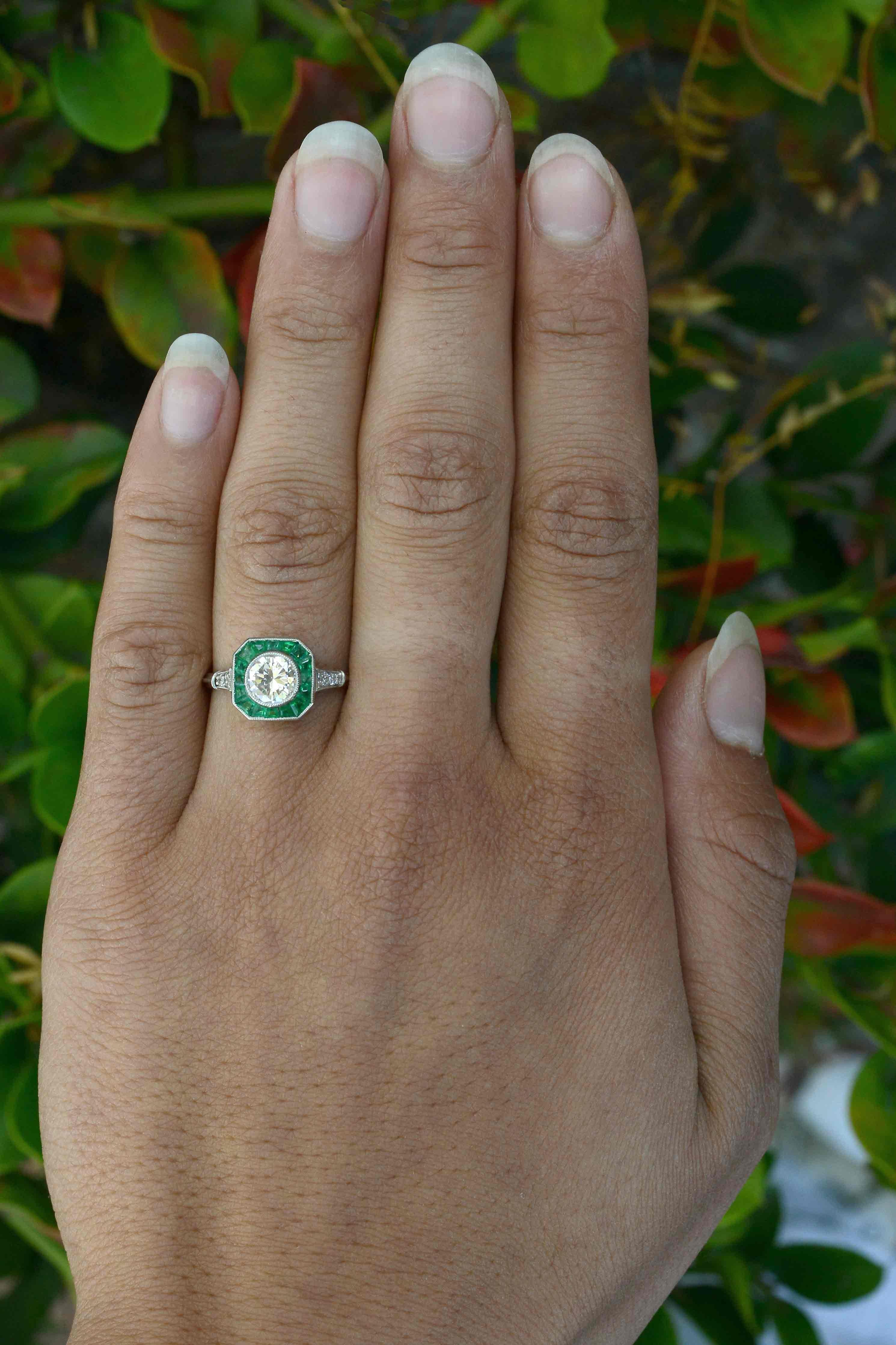 A captivating Art Deco Style diamond emerald engagement ring. The revivalist design, so sleek and geometric is centered by 3/4 carat diamond solitaire of a captivating brilliance and exceptional clarity. The octagon outline features a bevy of bright
