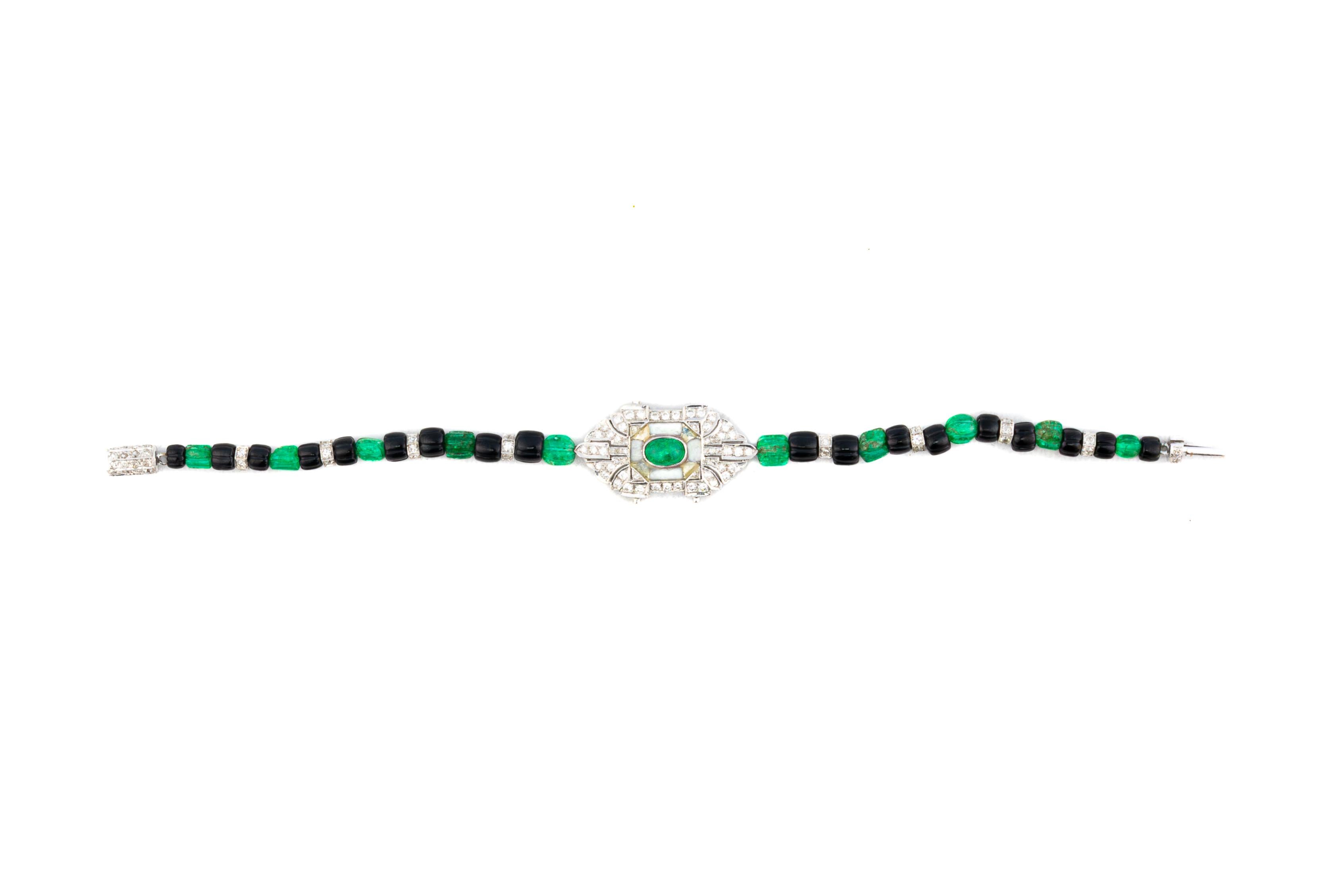 Bracciale Art Déco con diamanti, smeraldi e onice

Un elegante bracciale Art Déco centrato da una placca geometrica di diamanti con uno smeraldo ovale incorniciato da onice e diamanti a taglio singolo. La placca è infilata con un'alternanza di