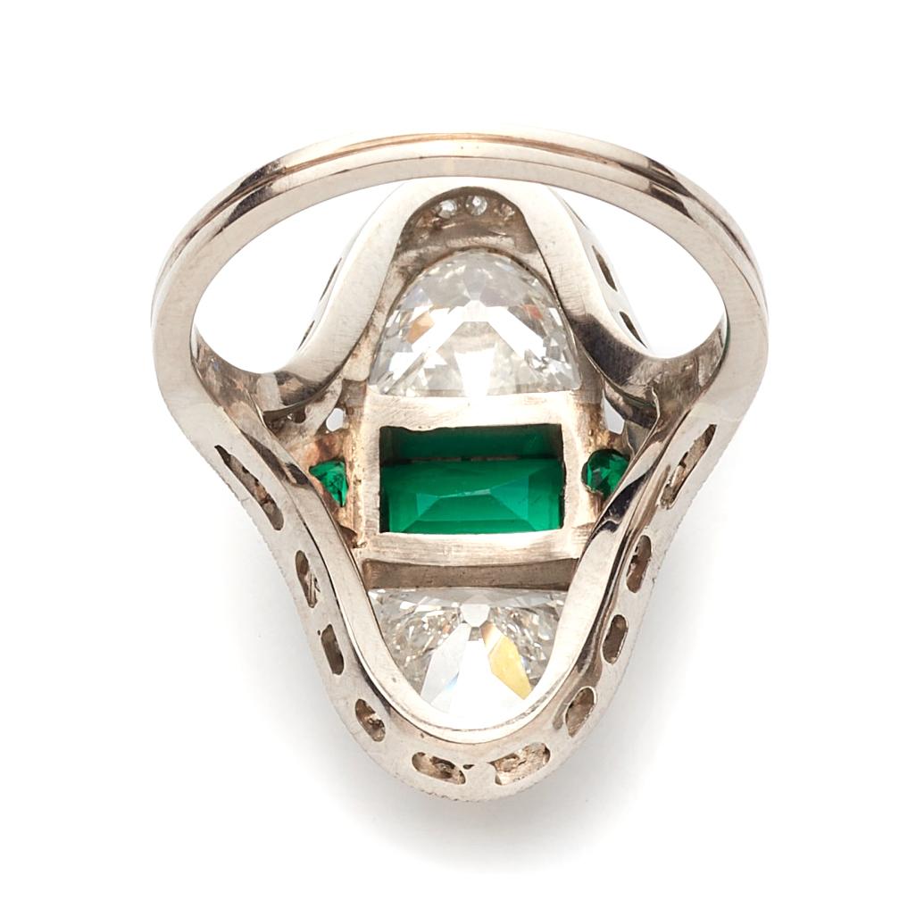 This beautiful Art Deco ring from the early 19th century is set with two beautiful half moon old cut diamonds and three fine Columbia emeralds outlined with numerous small round cut diamonds.
The arc form was applied in many buildings and structures