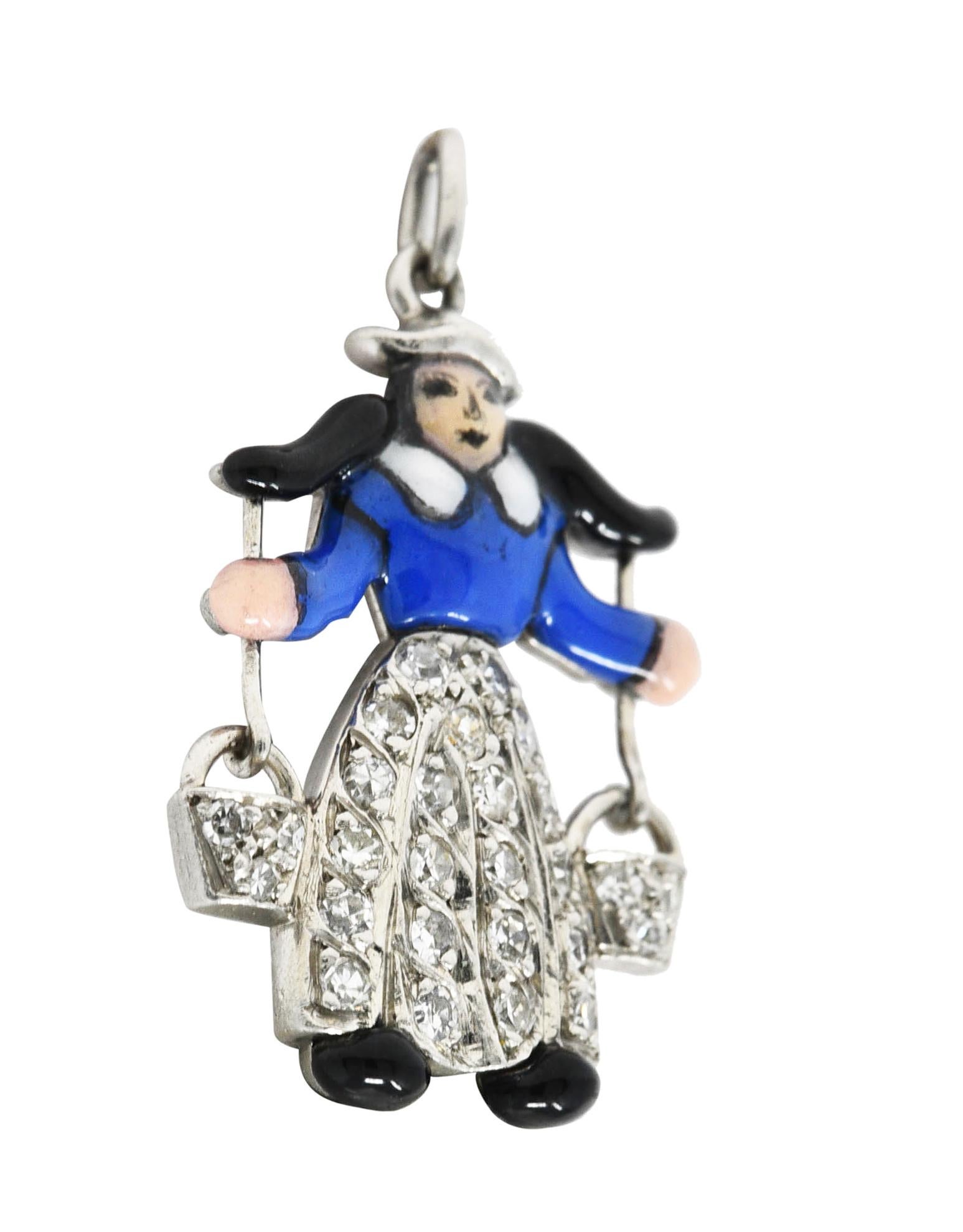 Designed as an enamel milkmaid in traditional Dutch clothing carrying yolk style buckets. Opaque glossy black, white and royal blue - exhibiting minimal loss. With single cut diamonds bead set in skirts and buckets. Weighing approximately 0.15 carat