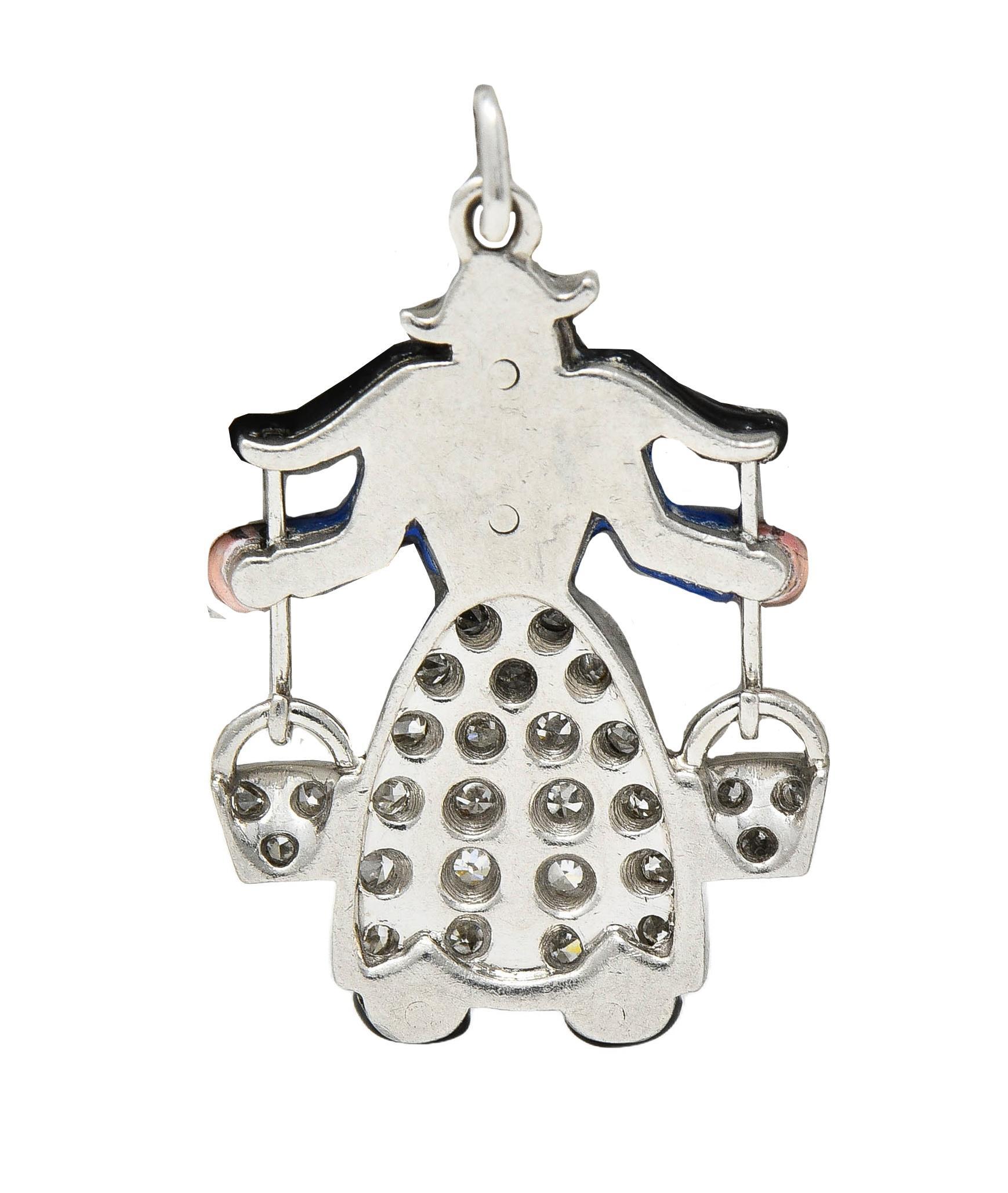 Designed as an enamel milkmaid in traditional Dutch clothing carrying yoke-style buckets
Opaque glossy black, white, and royal blue - exhibiting minimal loss
With single cut diamonds bead set in skirts and buckets
Weighing approximately 0.15 carat