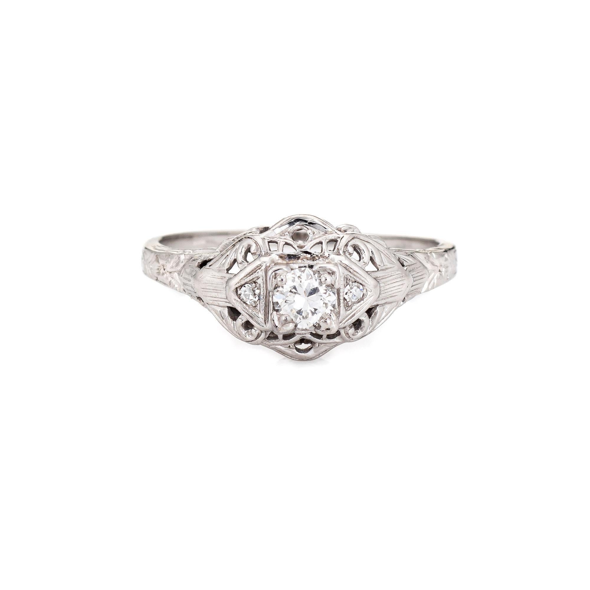 Finely detailed vintage Art Deco diamond engagement ring (circa 1920s to 1930s) crafted in 18 karat white gold. 

One old European cut diamond is estimated at 0.25 carats (estimated at H-I color and SI1 clarity). Two diamonds accent the center stone
