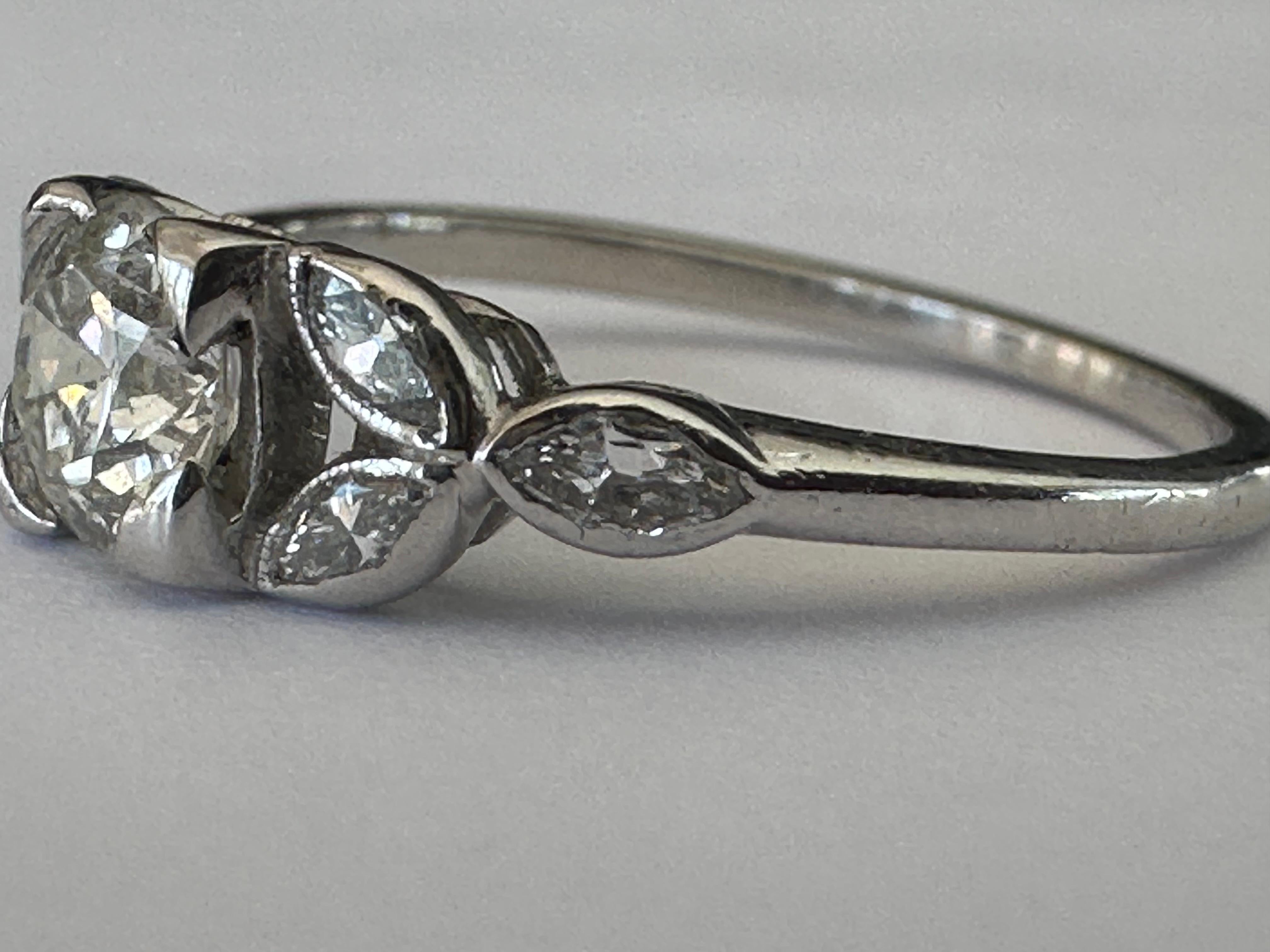 In this Art Deco ring, an Old European-cut diamond center stone measuring 5mm and approximately 0.50-carats radiates between trios of glittering marquise diamonds totaling 0.50 carats that form a lovely leaf-like design. Set in platinum. 