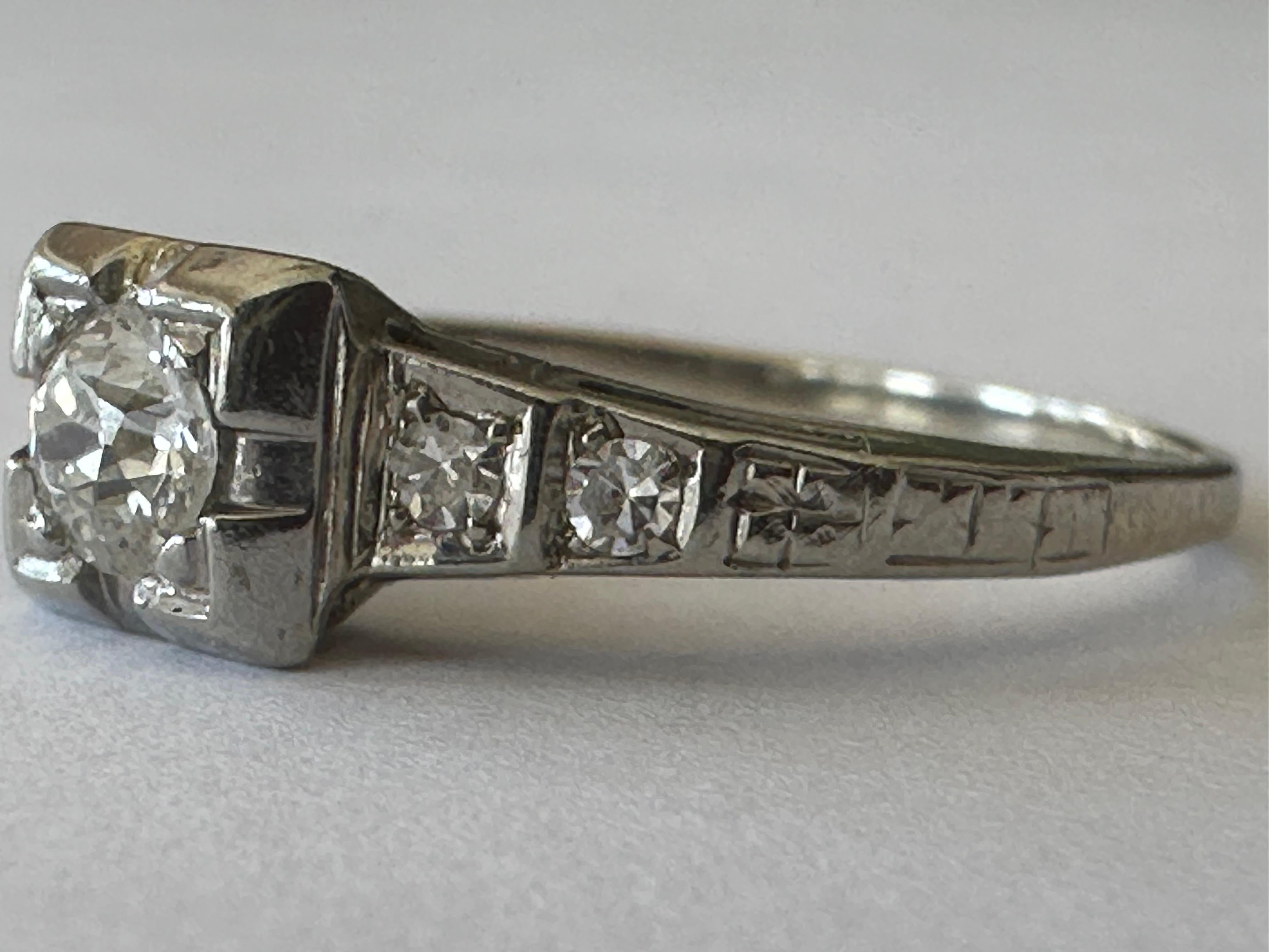 An Old European-cut diamond center stone measuring approximately 0.25 carat, H color VS clarity, shines brilliantly between tapered shoulders set with gently graduated pairs of single-cut diamonds leading to a hand engraved shank. Set in 14K white