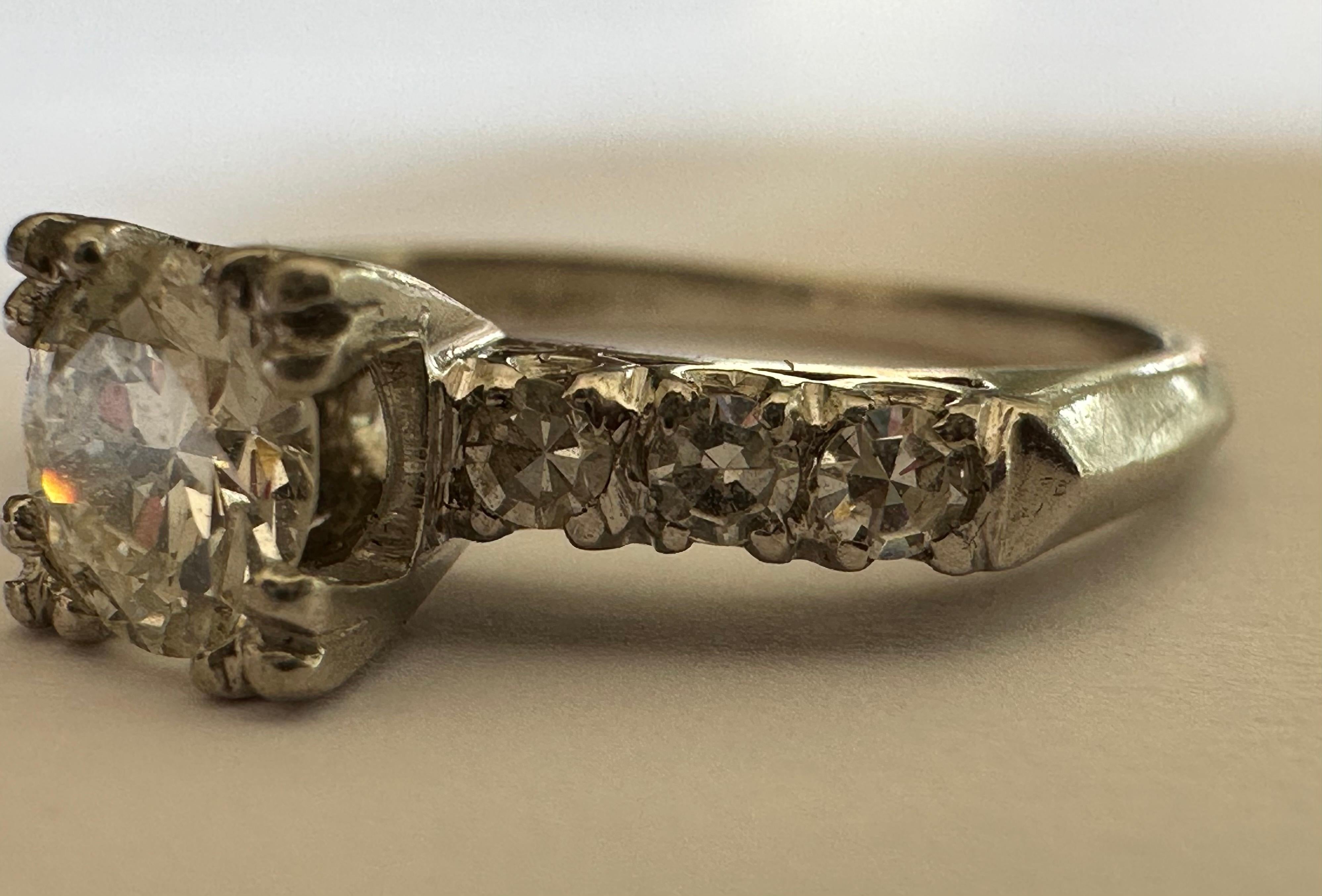Un diamant de taille européenne mesurant environ 0,50 carat, de couleur G et de pureté VS, brille au centre de cette pierre précieuse de la fin de l'époque Art déco, accentuée par six diamants taille unique étincelants, trois de chaque côté, d'une