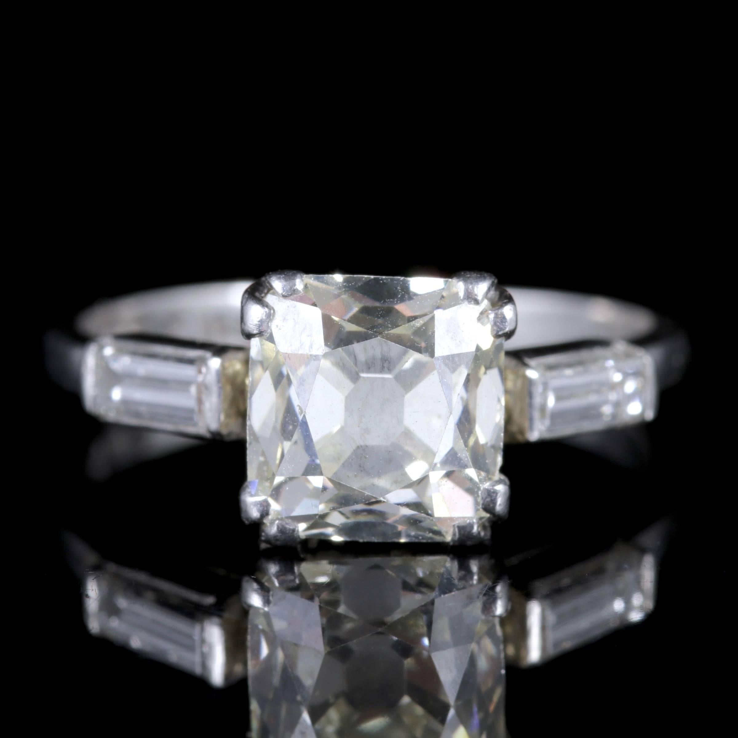 This fabulous all Platinum Art Deco Diamond ring boasts a spectacular 1.80ct cushion cut square Diamond which is all original to the shank.

Two beautiful bright white baguette Diamonds compliment the shoulders of this amazing ring.

The large