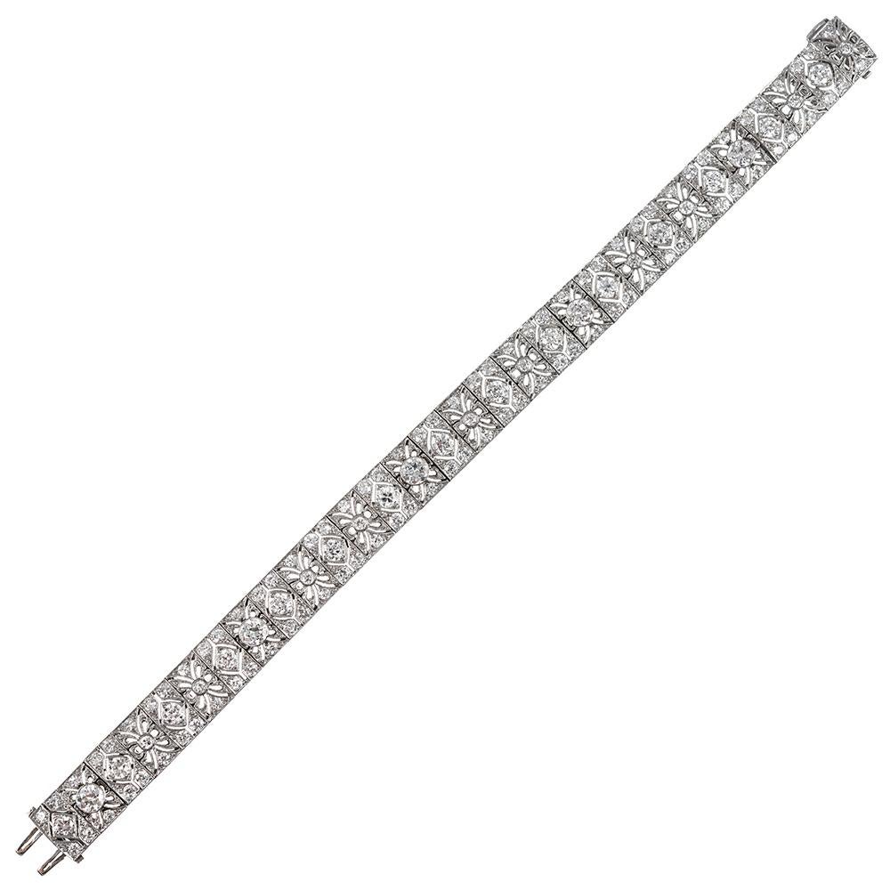 Beautiful, lacy open filigree is enhanced with 120 brilliant white diamonds that weigh 10.15 carats in total. The bracelet is made of platinum and measures 7 inches long and 3/8 of an inch wide. It is finished with an engraved safety. This piece