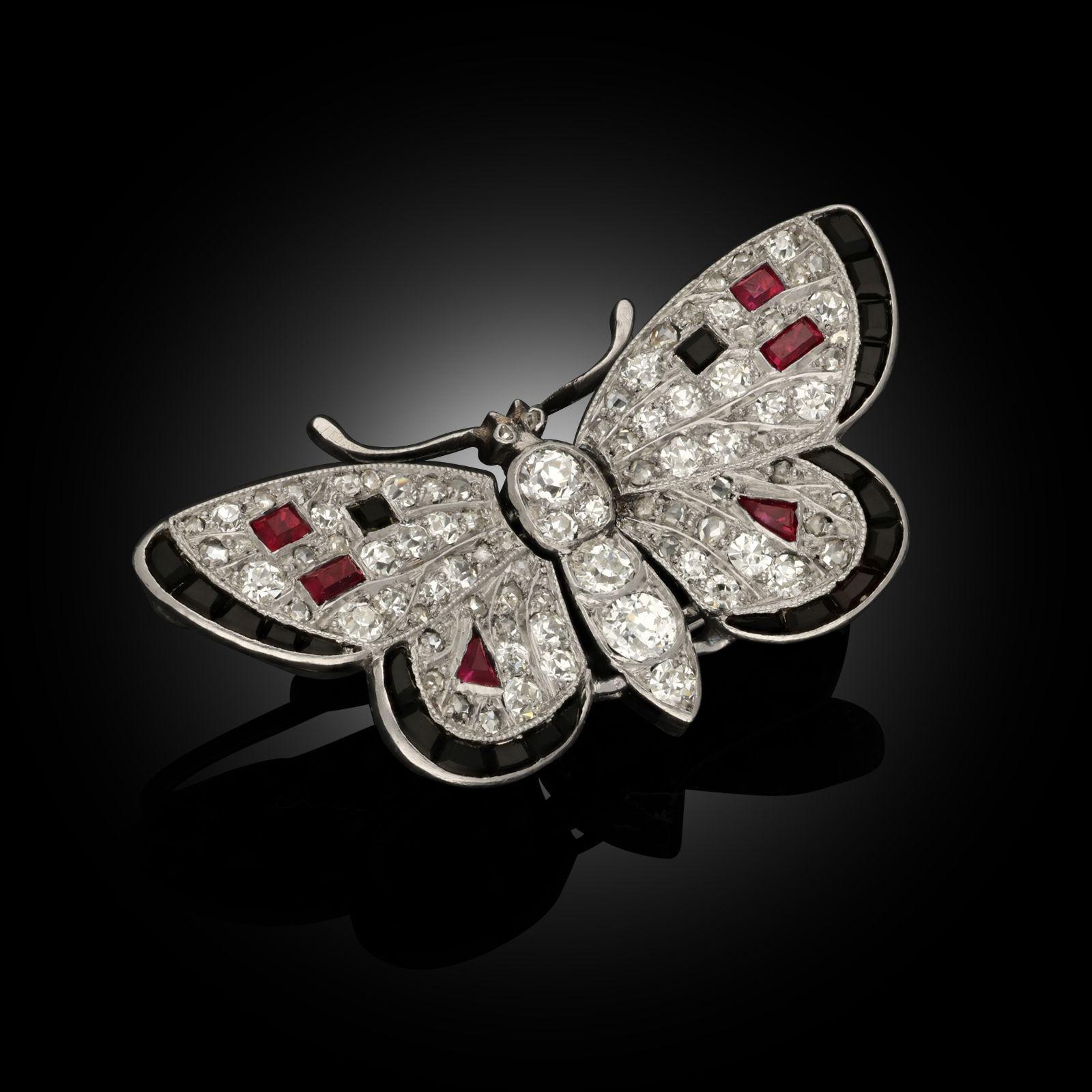Art Deco Diamond & Gemset Butterfly Brooch
An Art Deco diamond and gemset butterfly brooch, circa 1925. The petite open winged butterfly brooch is fully diamond set with ruby and onyx accents to the wings and platinum millegrain detailing, a diamond