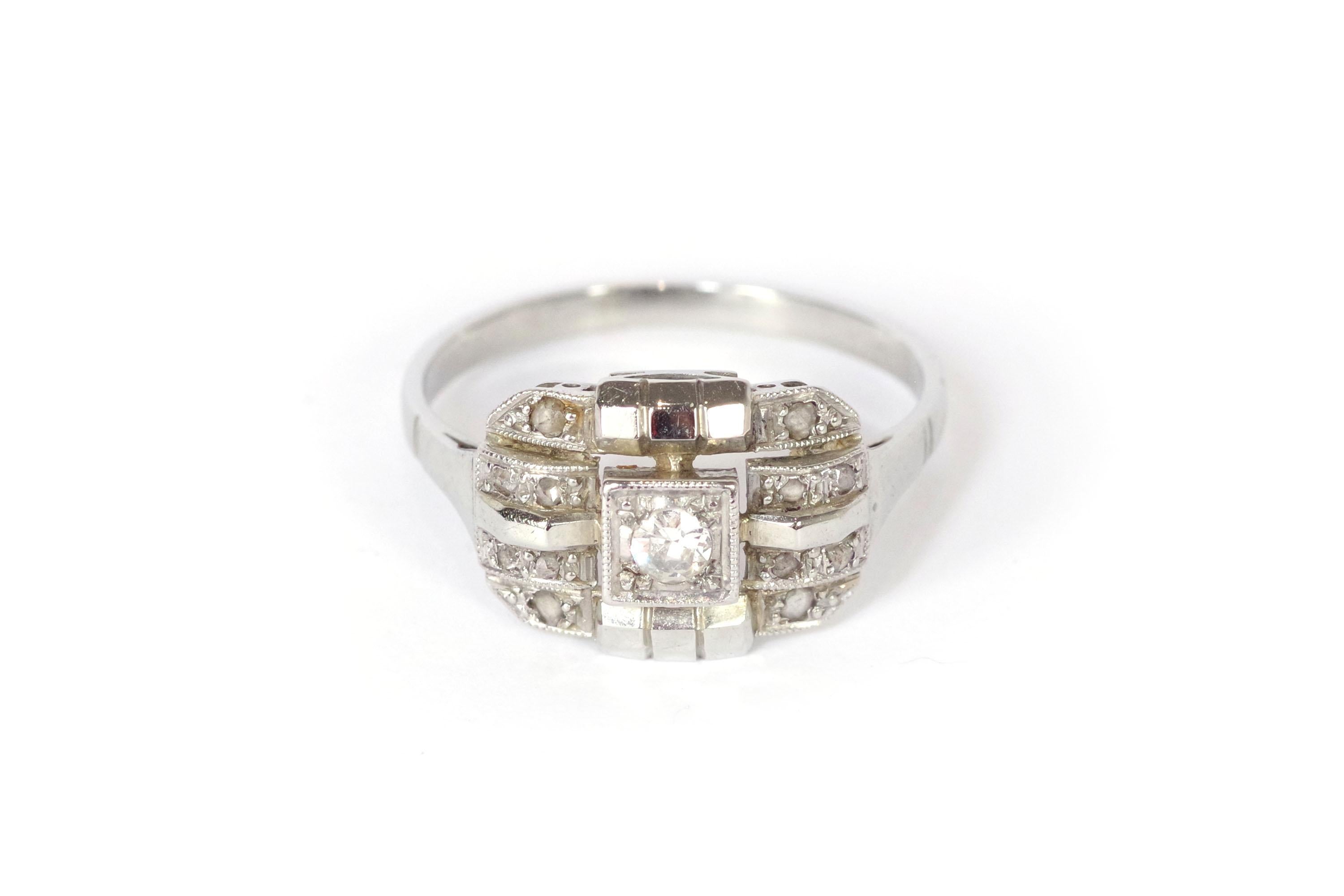 Art Deco diamond geometric ring in 18 karat white gold and platinum. This rectangular-shaped Art Deco ring is centered with a brilliant-cut diamond set within a square setting. The ring features geometric lines in gold, some polished and some