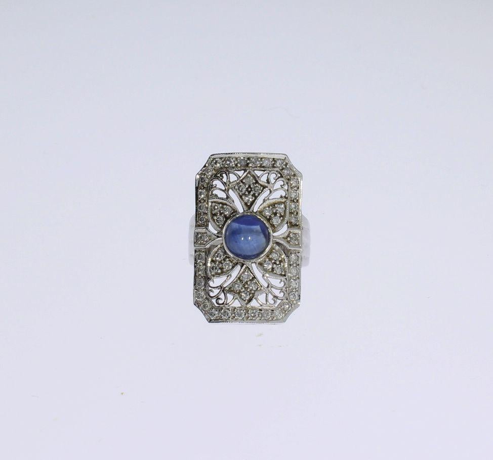 France 20th Century. Art Deco style. Mounted in 18 K white gold. Rectangular openworked front, set with a cabochon-cut sapphire weighing 1,57 carats, accompanied by 54 swiss-cut diamonds weighing total 0,54 carats clarity SI, wesselton. Hallmarked