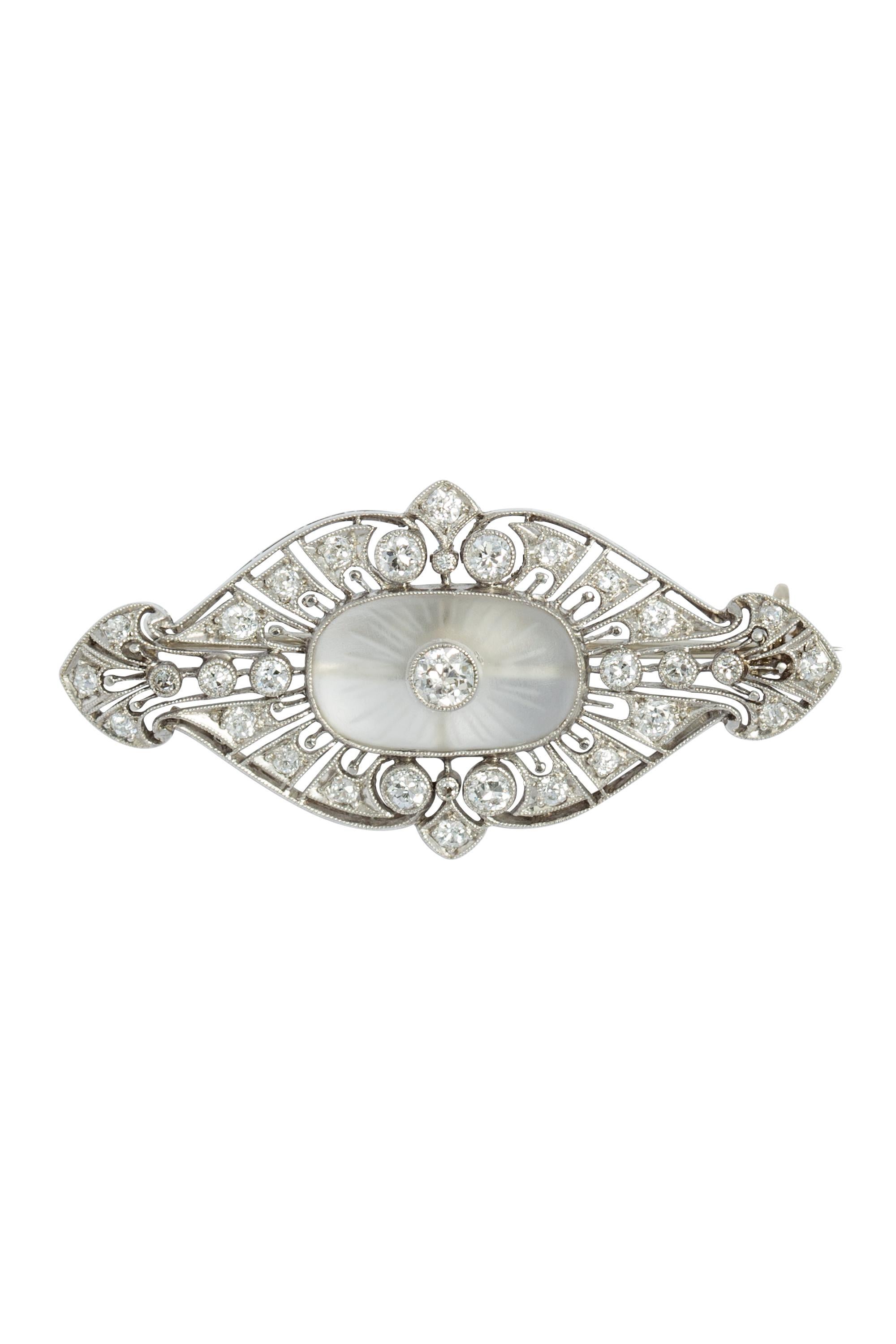 This brooch exudes true charm with its intricate design, featuring an openwork lace-like setting that is adorned with European cut diamonds, elegantly nestled in bezel and bead settings and delicately accented by milgrain detailing. This antique Art