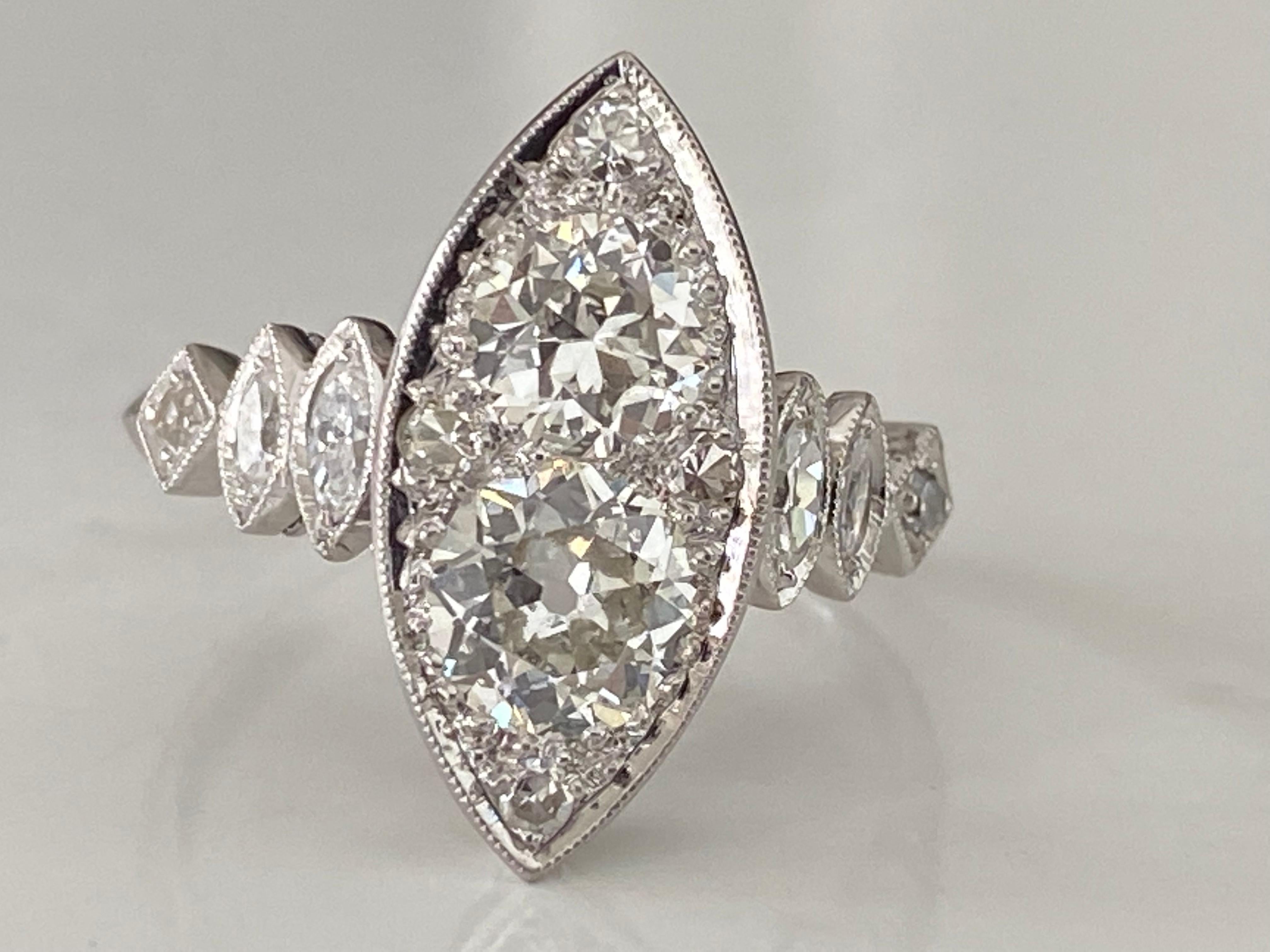 Ce bijou Art déco réalisé à la main en platine présente deux diamants étincelants de taille Vieille Europe totalisant environ 1,30 carat qui scintillent au centre d'un fond en forme de navette constellé de quatre diamants taille unique. Quatre