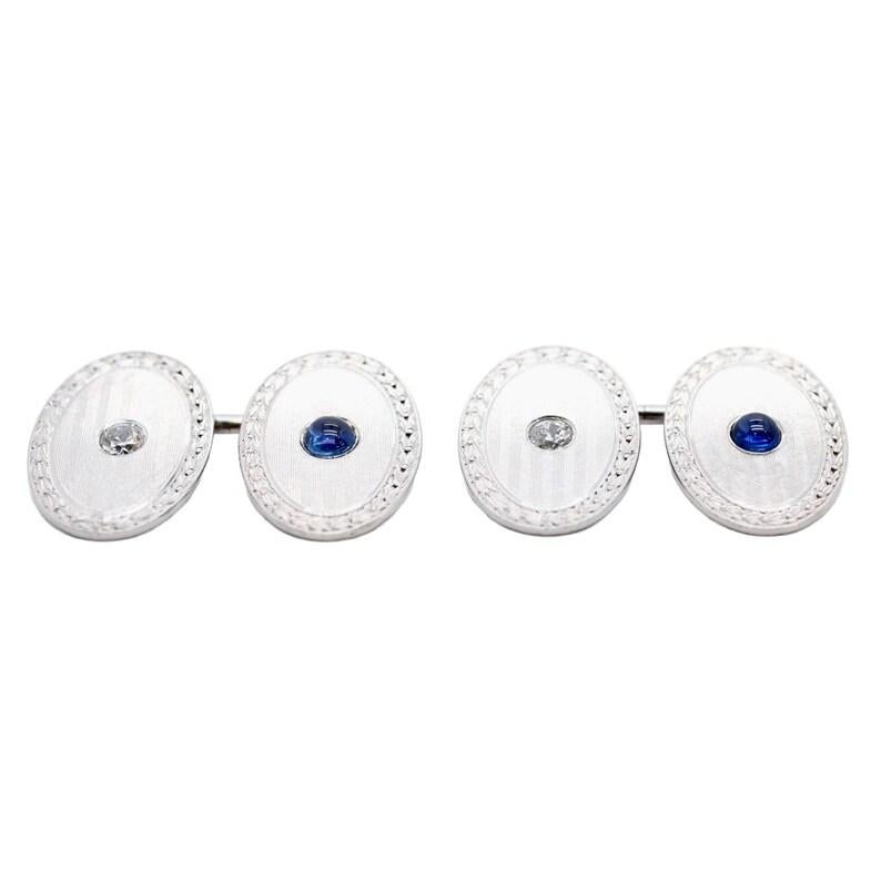 Aston Estate Jewelry Presents:

A pair of Art Deco period night and day cufflinks in platinum. Set with an old European cut diamond on one side, and a cabochon cut No Heat sapphire on the other side. Of G color and VS clarity, the two diamonds weigh