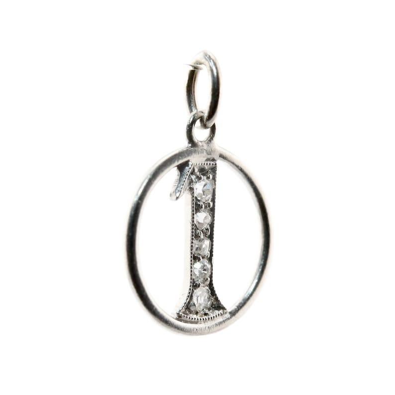Aston Estate Jewelry Presents:

A number 1 charm, set with antique mine cut diamonds. Crafted in platinum this original 1920's jewel features five petite mine cut diamonds of 0.08ctw.

Tests as Platinum.

Measurements: 10mm diameter.

Weight: 0.6