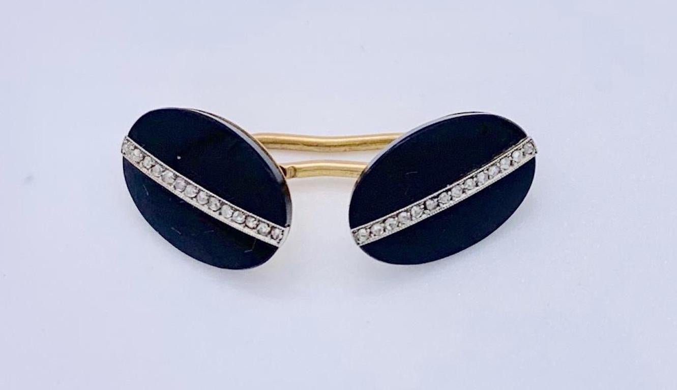 This very elegant pair of Art Deco cufflinks is made out of oval onyx plaques mounted in 14 k gold. They are decorated with a fine line of old cut diamonds in a mille grain platinum setting and have been made around 1910-1920. The cufflinks have