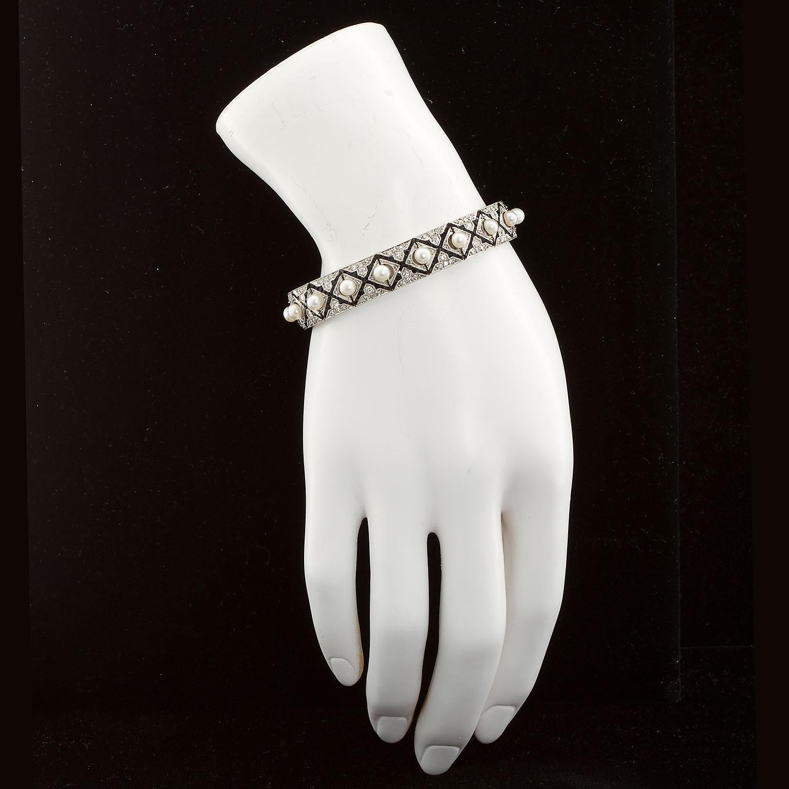 A very fine Art Deco period platinum and 18k gold bracelet with full-cut diamonds and calibrated onyx motif and cultured pearl centers. Fine craftsmanship throughout. The micro-setting of the diamonds and onyx is matched by the carefully centered