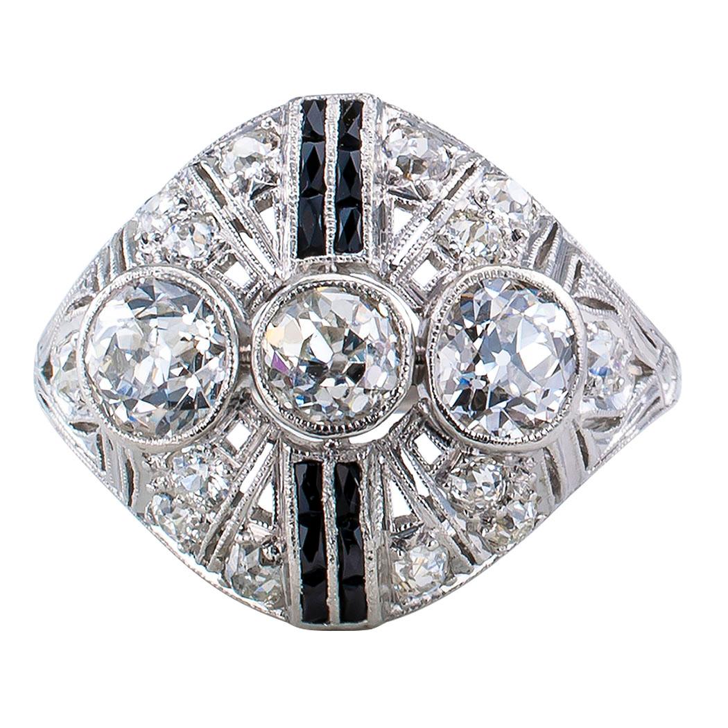 Art Deco diamond onyx and platinum dinner ring circa 1925. The rounded design features three larger European-cut diamonds bezel-set across the finger balanced by vertical, twin courses of French-cut black onyx stones, on a slightly domed, filigreed