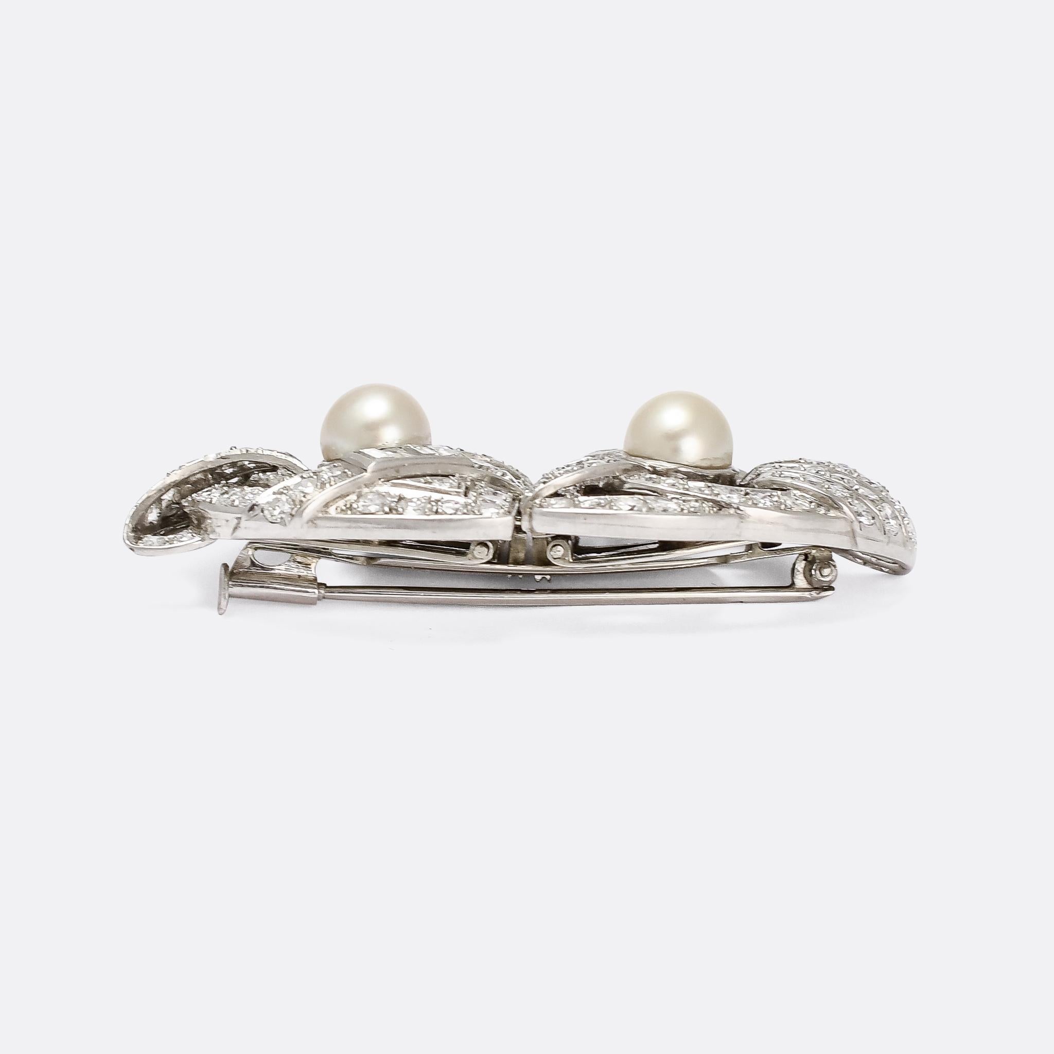 A stunning Art Deco period brooch that, quite ingeniously, splits in two to form a pair of dress clips. It's fully set with diamonds, brilliant cuts and baguettes, as well as two large pearls. It's crafted in platinum throughout, with French import