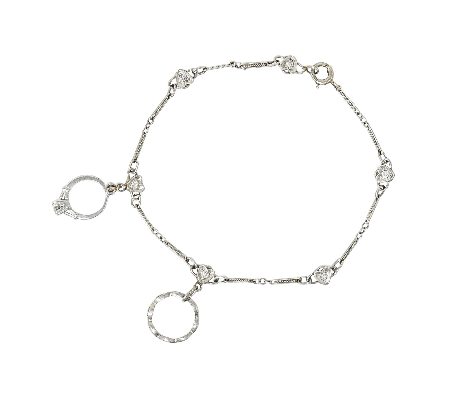 Comprised of a stylized platinum link chain with twisted rope and heart motif links. Suspending charms designed as a wedding band and an engagement ring. White gold and attached via jump ring links. With single cut diamonds throughout. Weighing