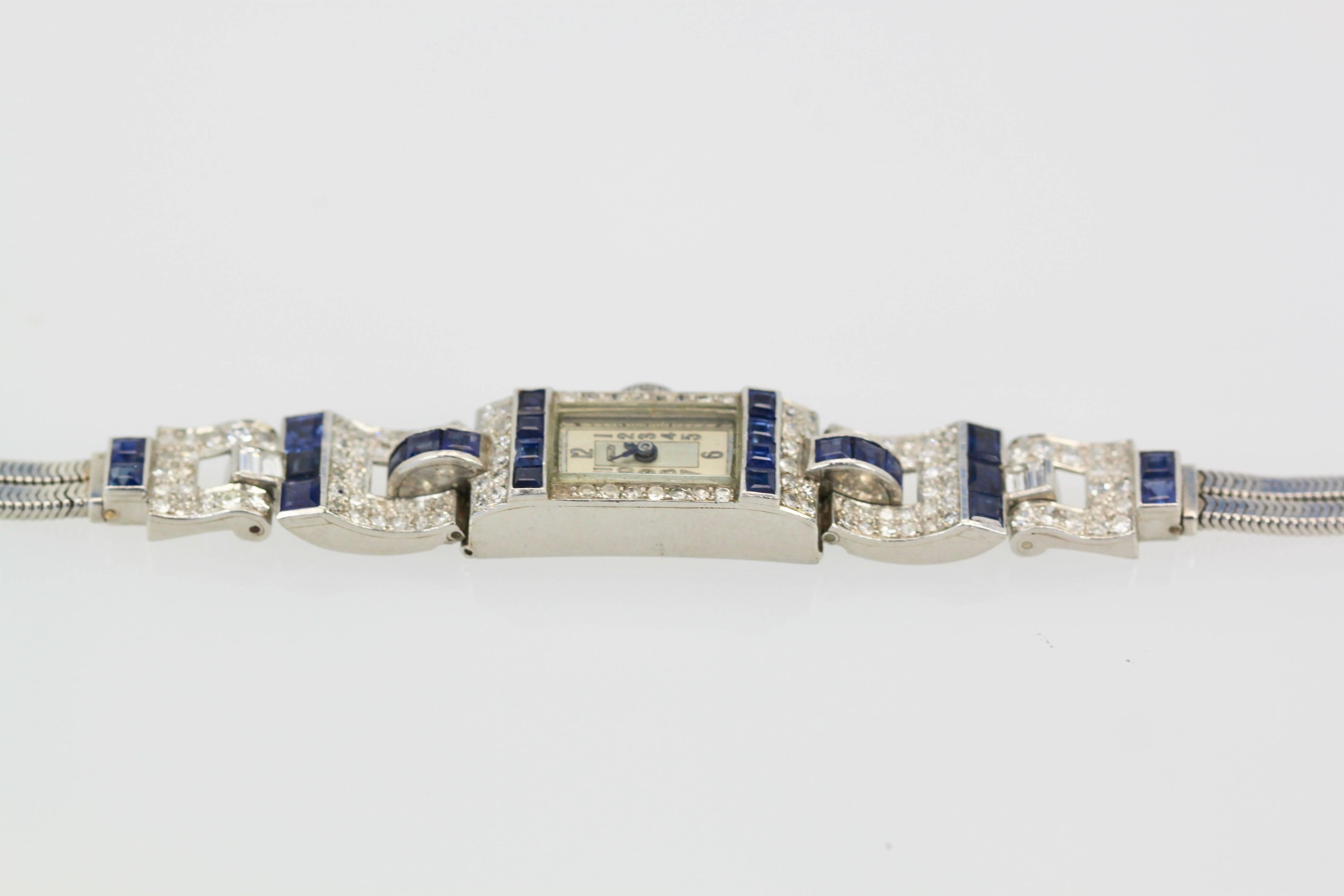 This gorgeous Art Deco platinum, diamond and sapphire bracelet watch was made circa 1935. It has a bit of a Retro feel because the Deco era was ending, and thus is Transitional. This can be seen in the way the bracelet articulates with geometric