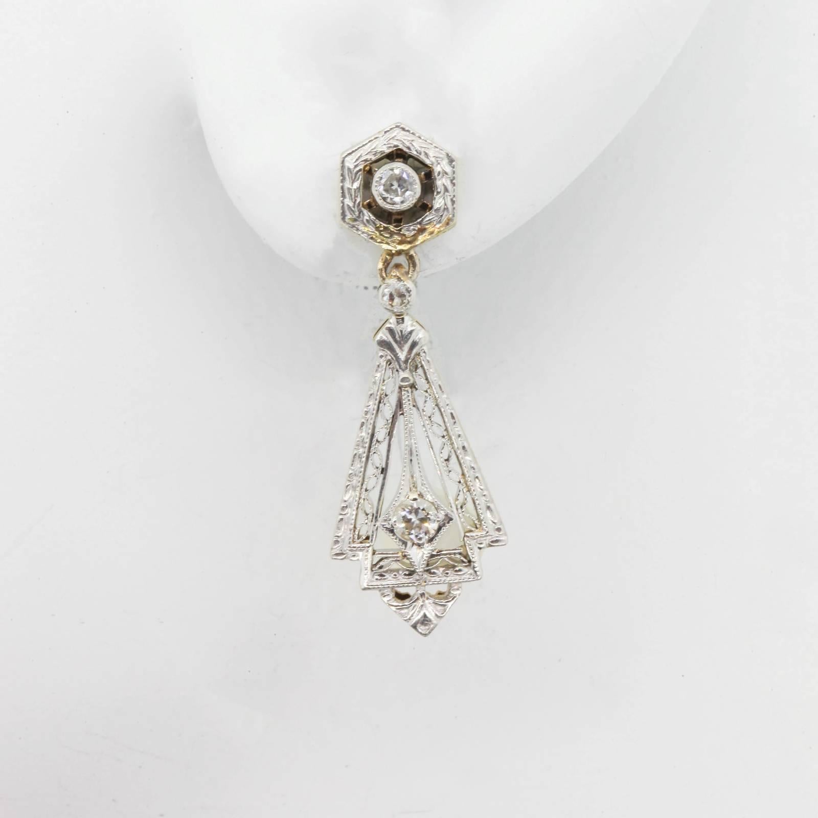 These antique earrings converge different lineal shapes resulting in a perfect union.  They are fabricated in platinum topped 14Kt yellow gold with delicate filigree and hand engraving, and are accented with 0.24 carart of old cut diamonds. 