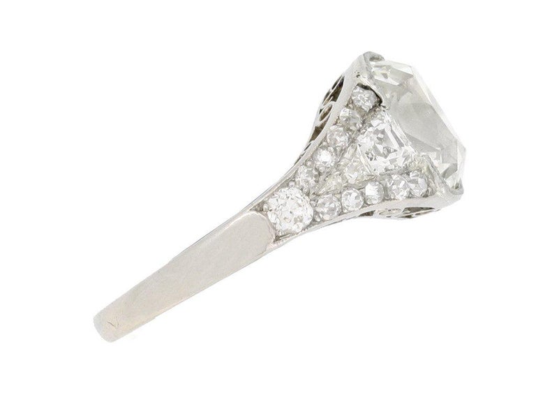 Art Deco diamond engagement ring. Set to centre with a cushion shape old mine diamond, K colour, VS2 clarity, with an approximate weight of 2.73 carats in an open back rubover millegrain setting, flanked by two tapered step cut diamonds with a
