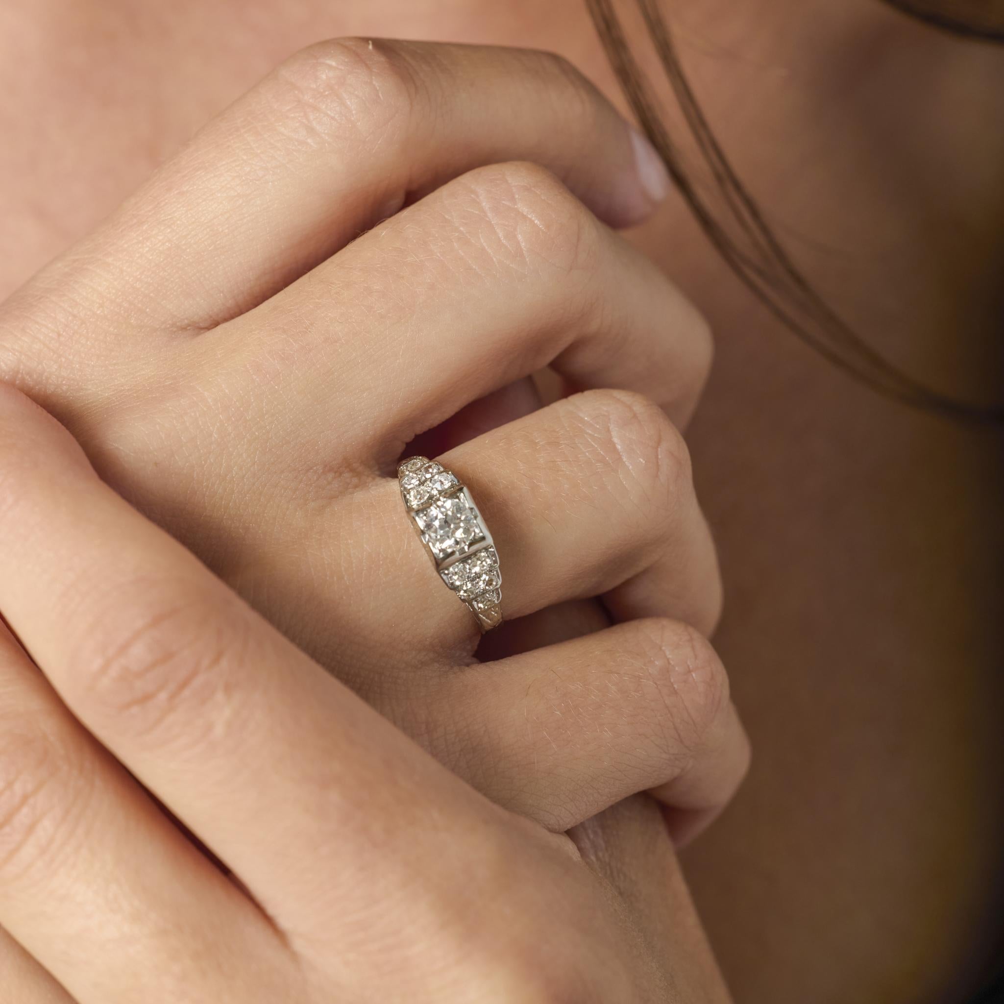 Questo elegante anello Art Deco in oro bianco 18 carati presenta un luminoso diamante taglio vecchio europeo circondato da dieci accenti a taglio singolo, che incarna il raffinato glamour e la maestria degli anni '30.