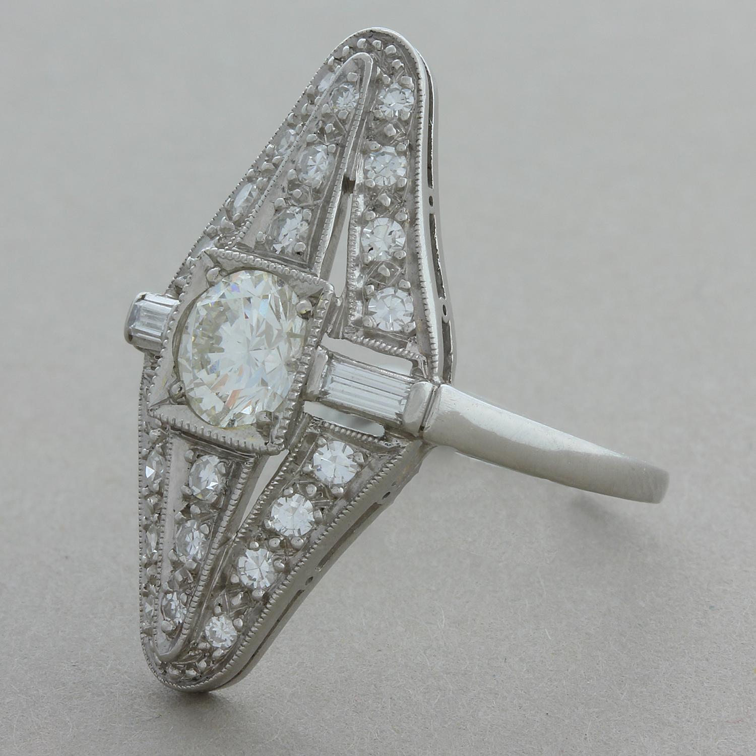 Cette bague de style Art déco classique comporte un gros diamant de taille européenne pesant environ 1,50 carat. Il est ensuite accentué par 1 carat de pierres plus petites, rondes et deux coupes baguette autour de la pierre centrale. Fabriquée à la