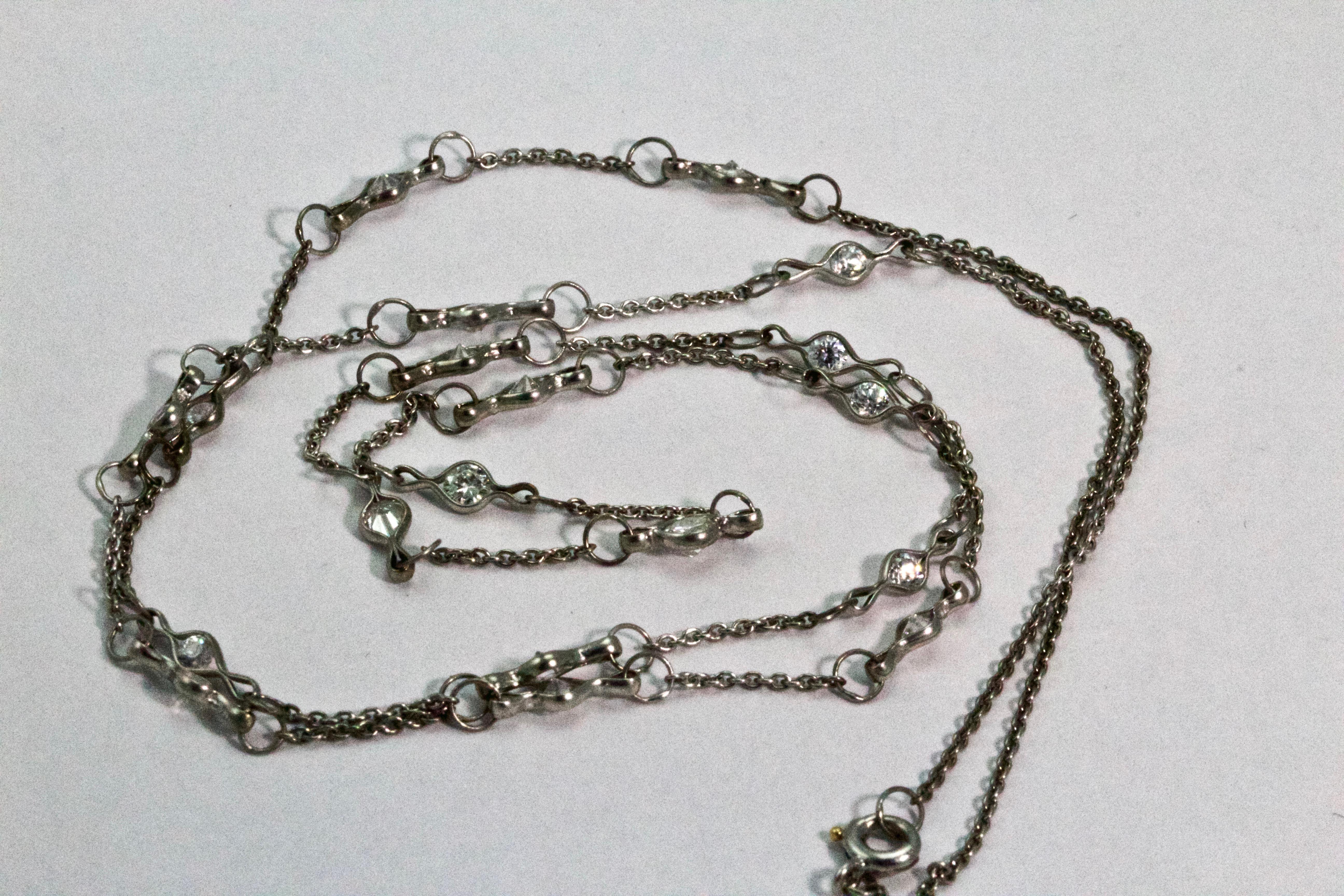 Fashioned circa 1920s this Art Deco long chain is comprised of platinum cable style links to give a chain of approximately 23 inches long. Beautifully embellished with 19 Old European cut diamonds in stylised links. The largest central diamond