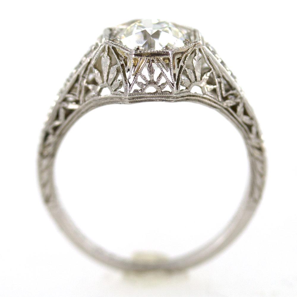 Brilliant Art Deco Diamond Platinum Engagement Ring. This hand crafted Deco ring is fashioned in platinum with a hexagon shaped top and filigree work throughout. A center  1.53 Carat Old European Cut Diamond has been graded by the GIA J color and