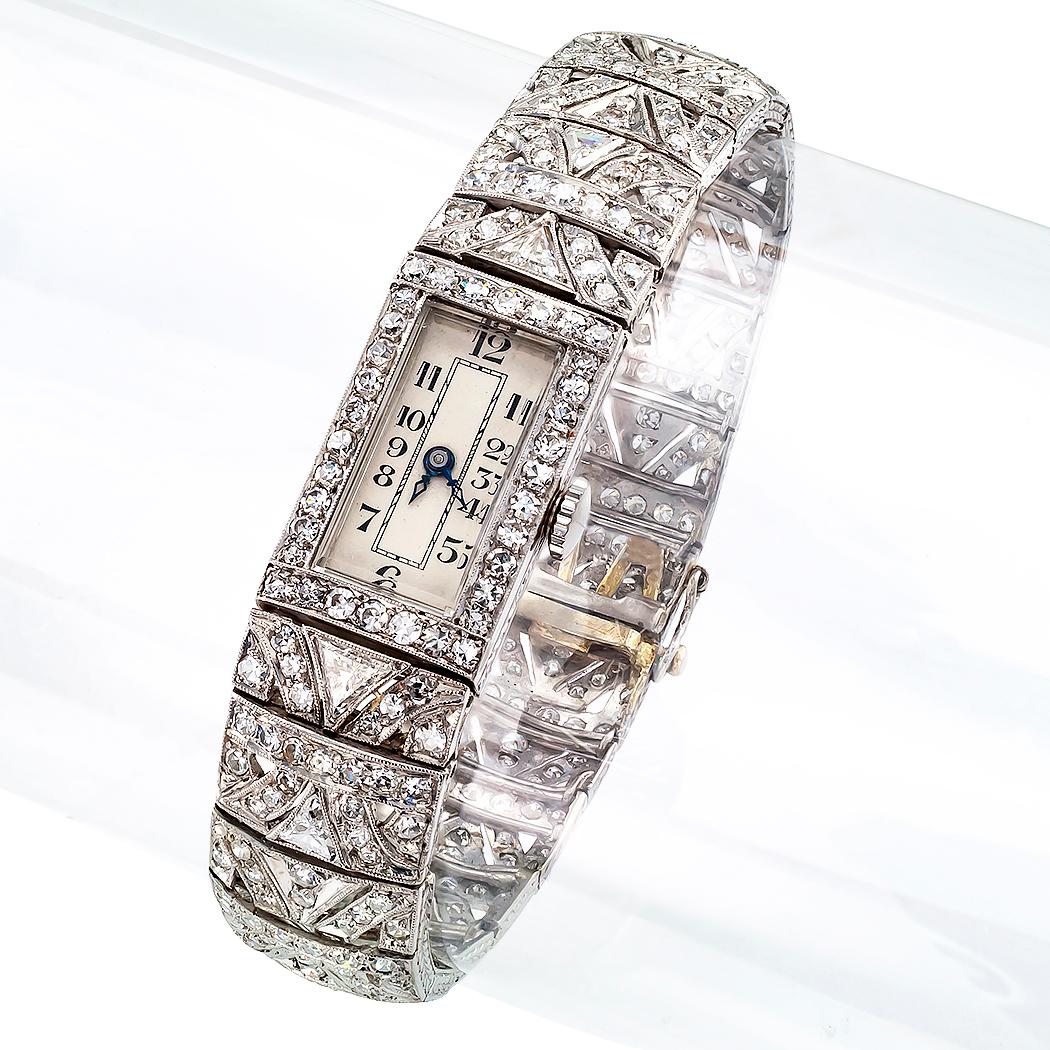 Art Deco Diamond and platinum wristwatch circa 1930. Featuring a rectangular white dial with black Arabic numerals, within a conforming diamond bezel, completed by a flexible bracelet entirely set with triangular and round diamonds all together