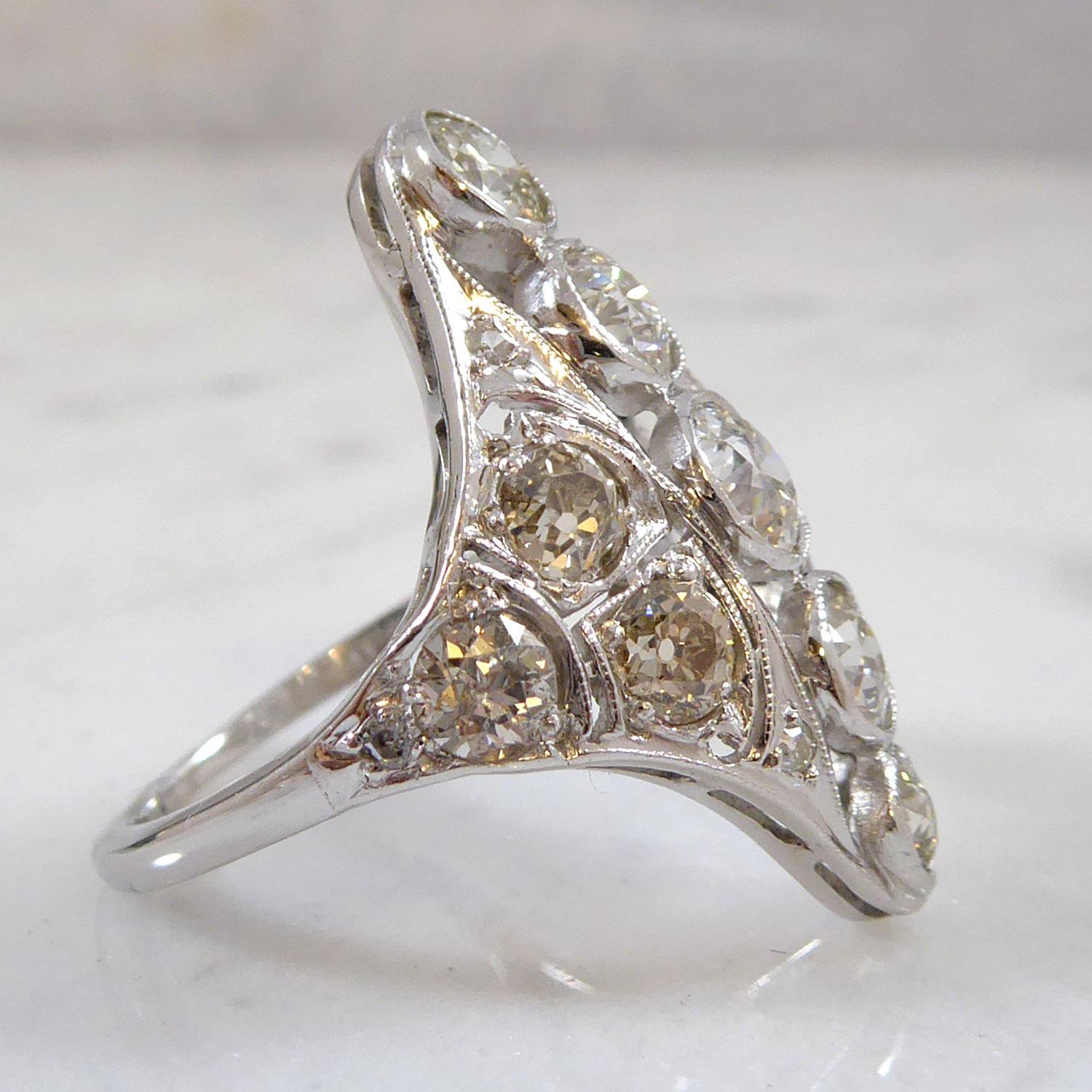 Art Deco diamond cluster ring.  A central row of five  old European cut diamonds  in rub over collar settings  leading down the finger to an open work panel and shoulders, each shoulder set with three rose cut diamond and three eight-cut diamonds. 