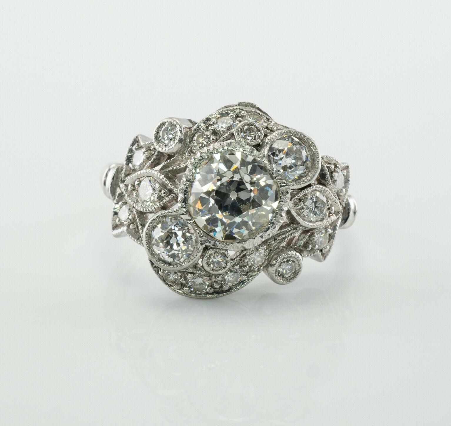 This vintage circa 1930s ring is finely crafted in luxurious Platinum and set with genuine Diamonds. The center Old Mine cut Diamond is 1.20 carat of VS2 clarity and J color. Two smaller bezel-set old mine cut total .40 carat. And more round cut