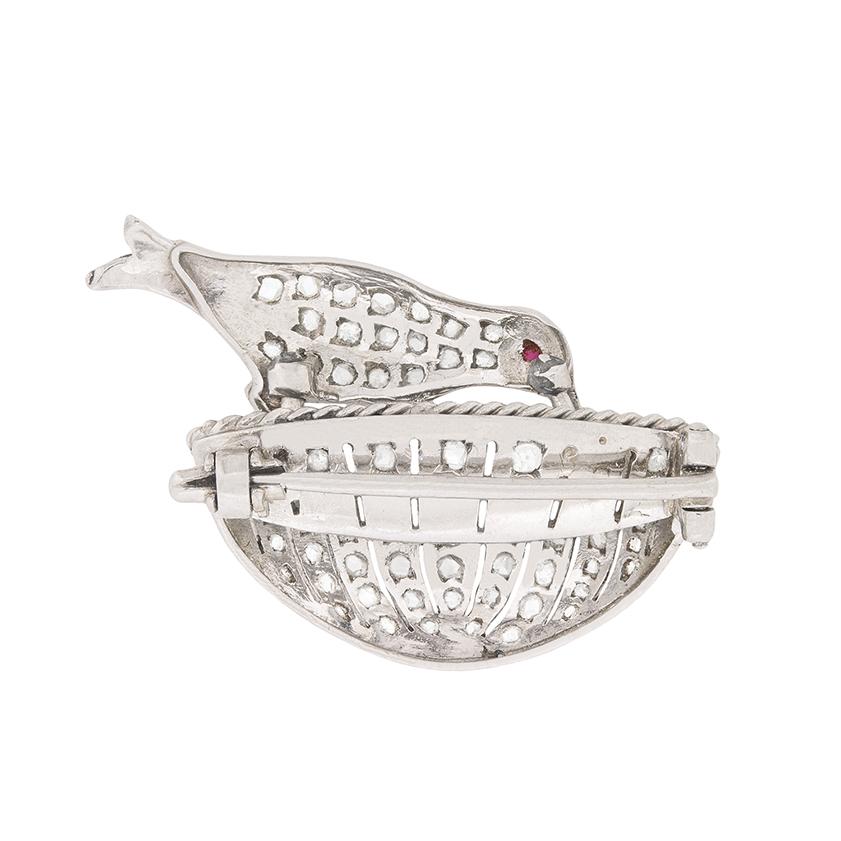 This delicate little brooch is made in the shape of bird in a basket all in platinum. The bird and basket and grain set with rose cut diamonds totalling 0.50 carat. The eye is a small ruby, 0.01 carat in weight and in the basket is a natural pearl.