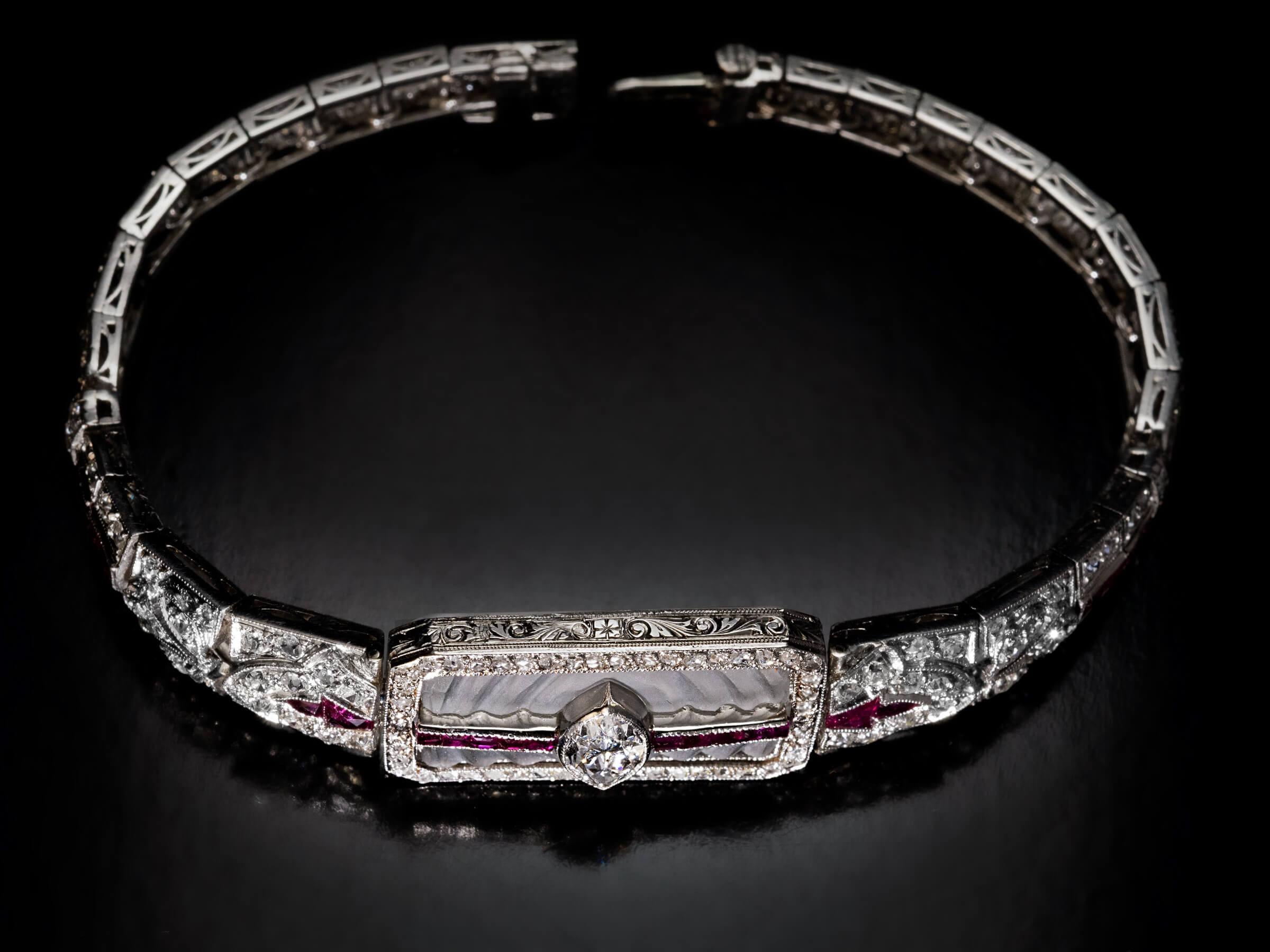 Circa 1910s  This antique early Art Deco era bracelet is finely handcrafted in platinum. The bracelet is centered with a frosted rock crystal plaque carved to imitate ripples in water. A bright white and clean marquise cut diamond (E color, VS1