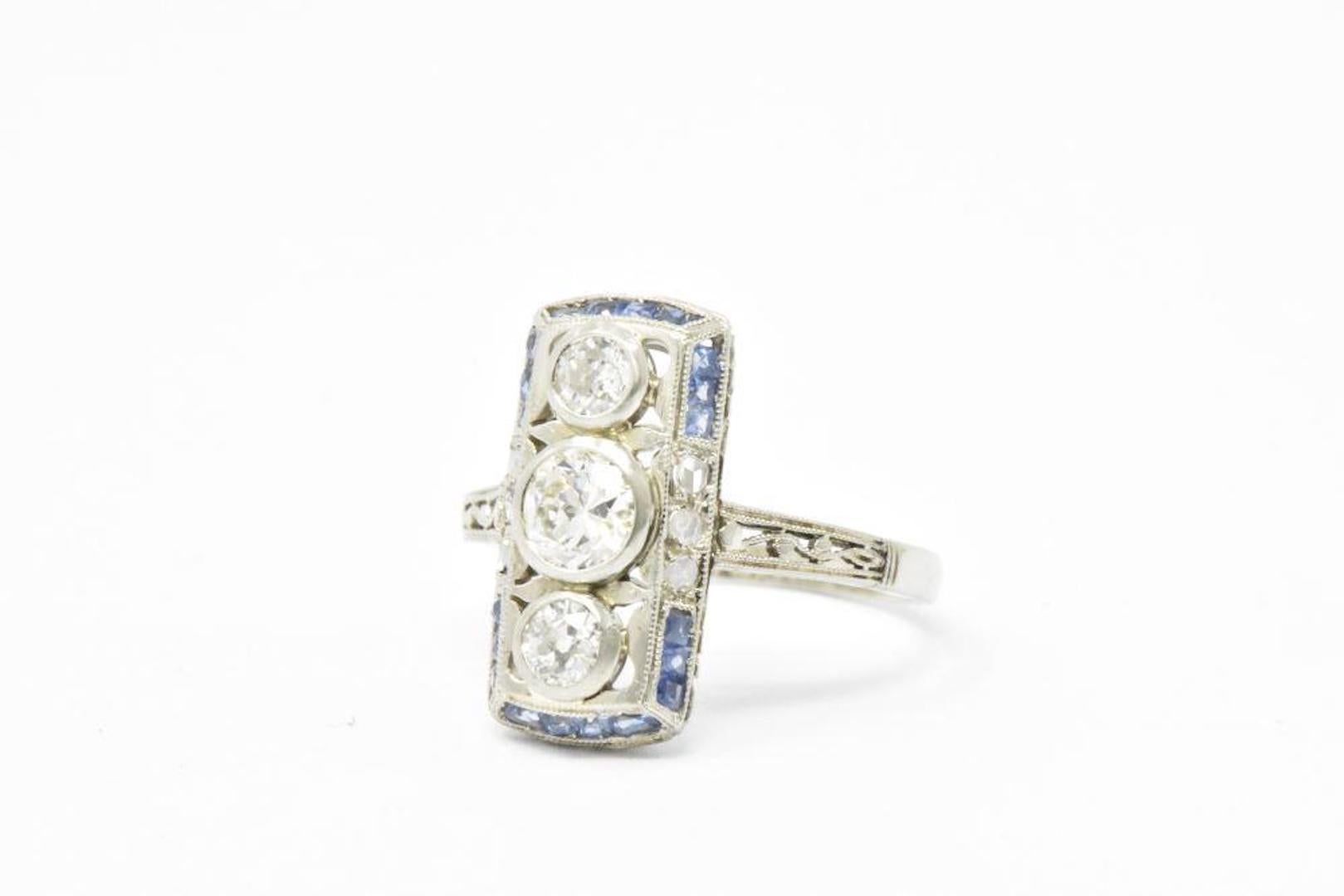 This is a beautiful Art Deco sapphire and diamond ring. This lovely ring is set in 18K white gold. The center old European cut diamonds are bezel set and weighing approximately 0.55 carats total, I/J color and VS clarity. A delicately alternating