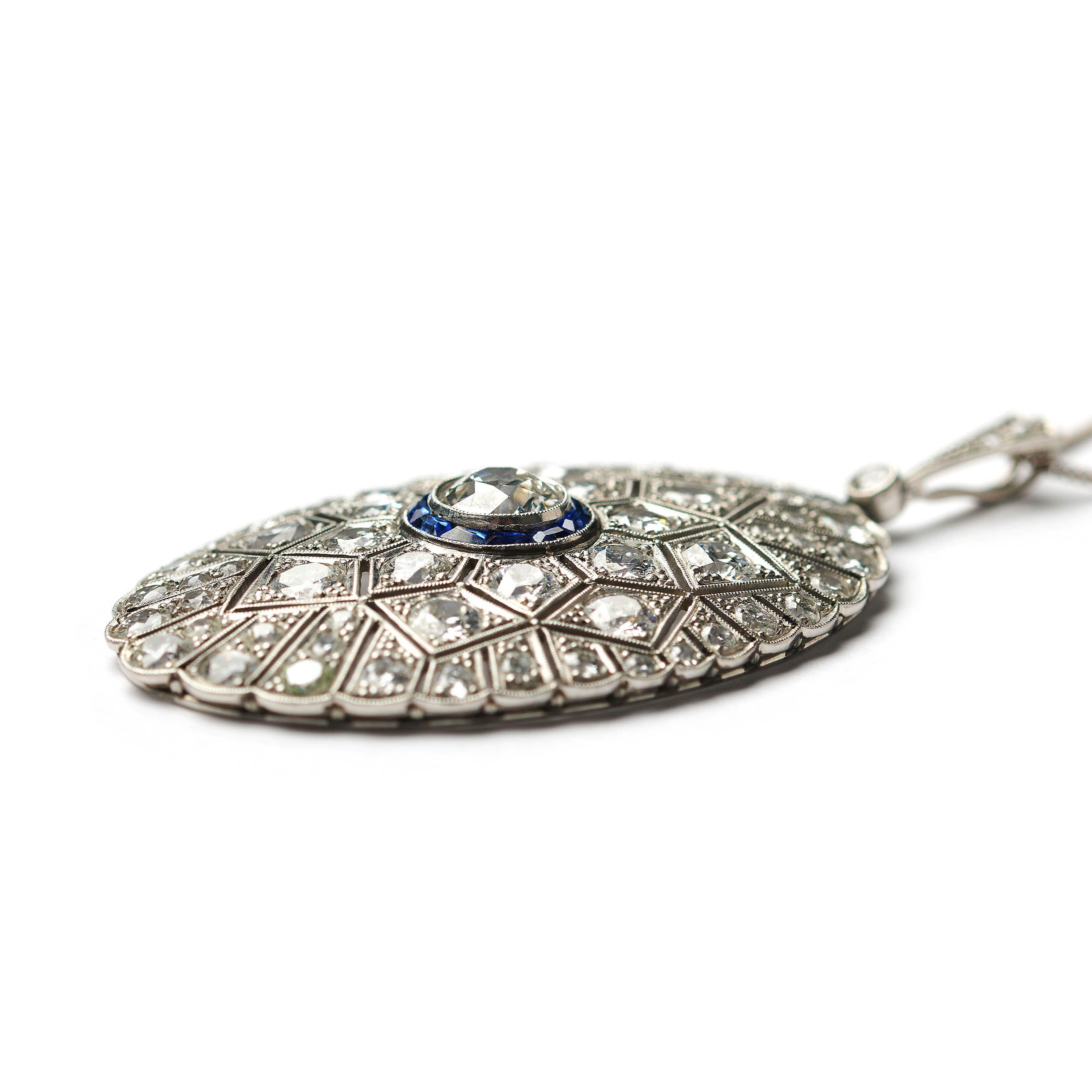 An Art Deco sapphire and diamond oval-shaped pendant, with an old-cut diamond, in the centre, weighing an estimated 1.50 carats, in our opinion the colour is I/J and our opinion of the clarity is SI, surrounded by a border of calibré cut blue