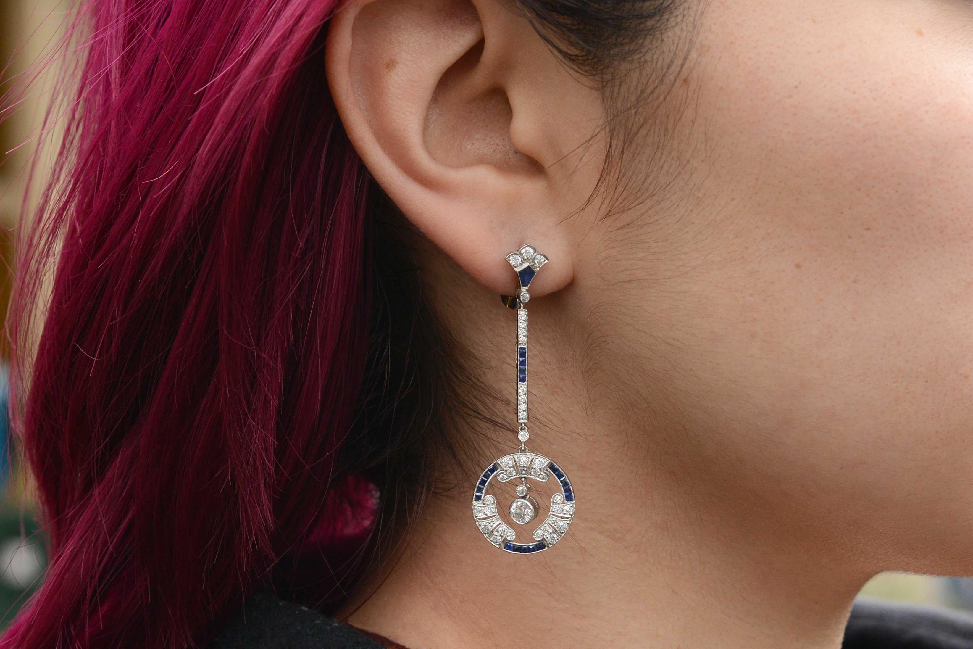 These long, dramatic Art Deco style dangle drop earrings sweep the shoulders and sway so seductively. Bursting with fire and brilliance, the old European cut diamonds and  French cut sapphires produce a geometric outline that is so sleek and modern