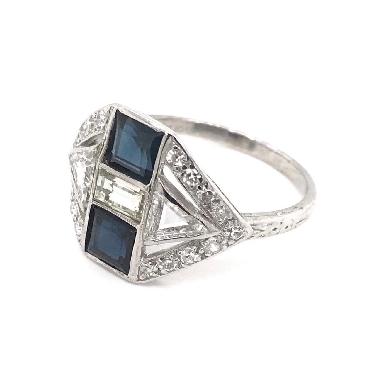 This antique piece was handcrafted sometime during the Art Deco design period ( 1920-1940 ). This incredibly unique ring features three different cuts of diamonds. The platinum setting features 18 round diamond accents, 2 trilliant cut diamond