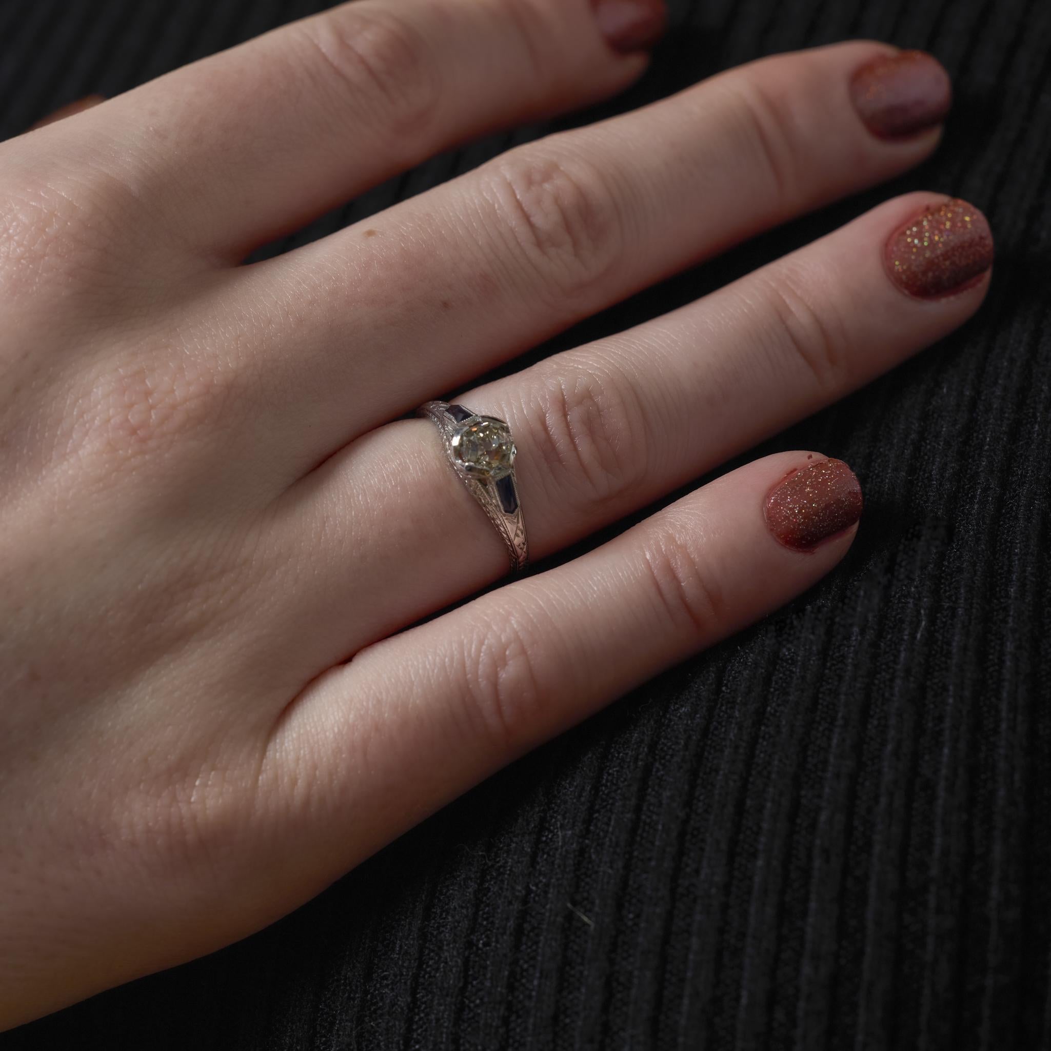 Este anillo Art Déco de platino presenta un diamante talla mina antigua de 0,65 quilates, de suave calidez vintage, flanqueado por dos llamativos zafiros talla bala. El contraste geométrico entre el diamante y el zafiro capta la audaz elegancia de