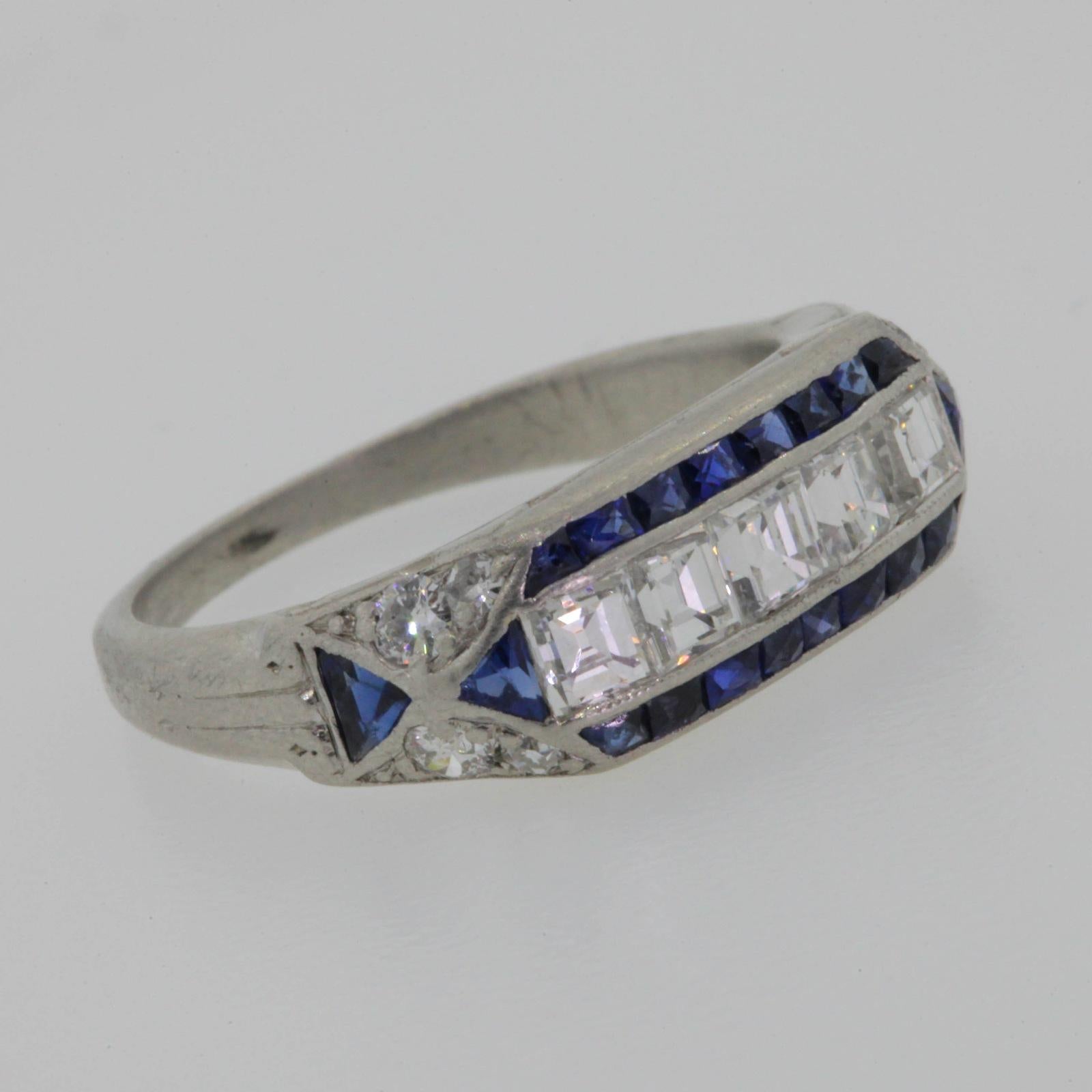 This beautiful, softly worn engraved platinum 1930 style ring features a row of five square cut diamonds, totally 0.65 carat.  Hugging the diamonds are two rows of calibrated French cut blue Ceylon Sapphires, four old cut Round diamonds and two