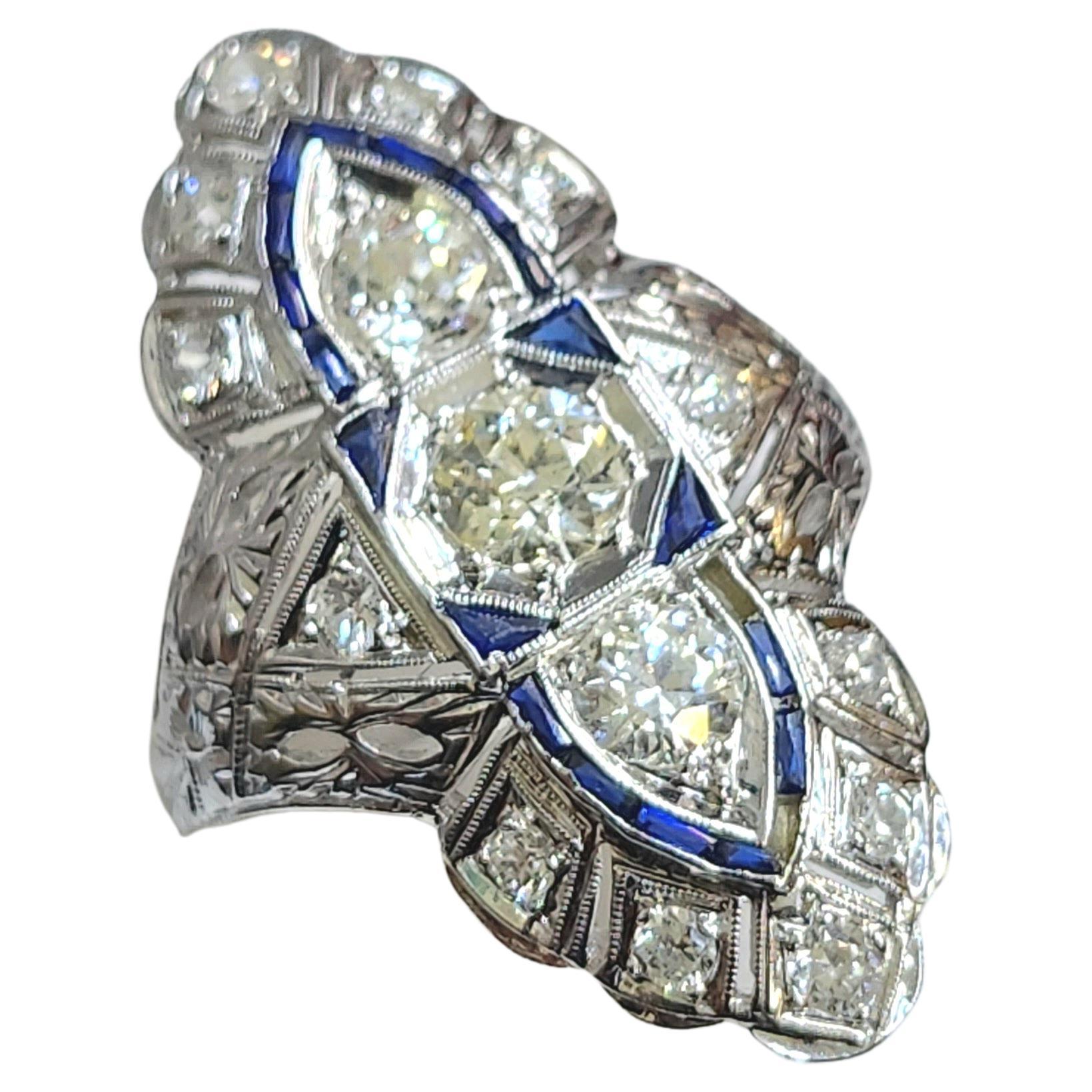 1920s orginal art deco period large ring with an estimate old cut diamond weight of 1.20 carars H color white vs clearity decorted with blue baguet cut sapphires ring head lenght 3 cm hall marked platinum