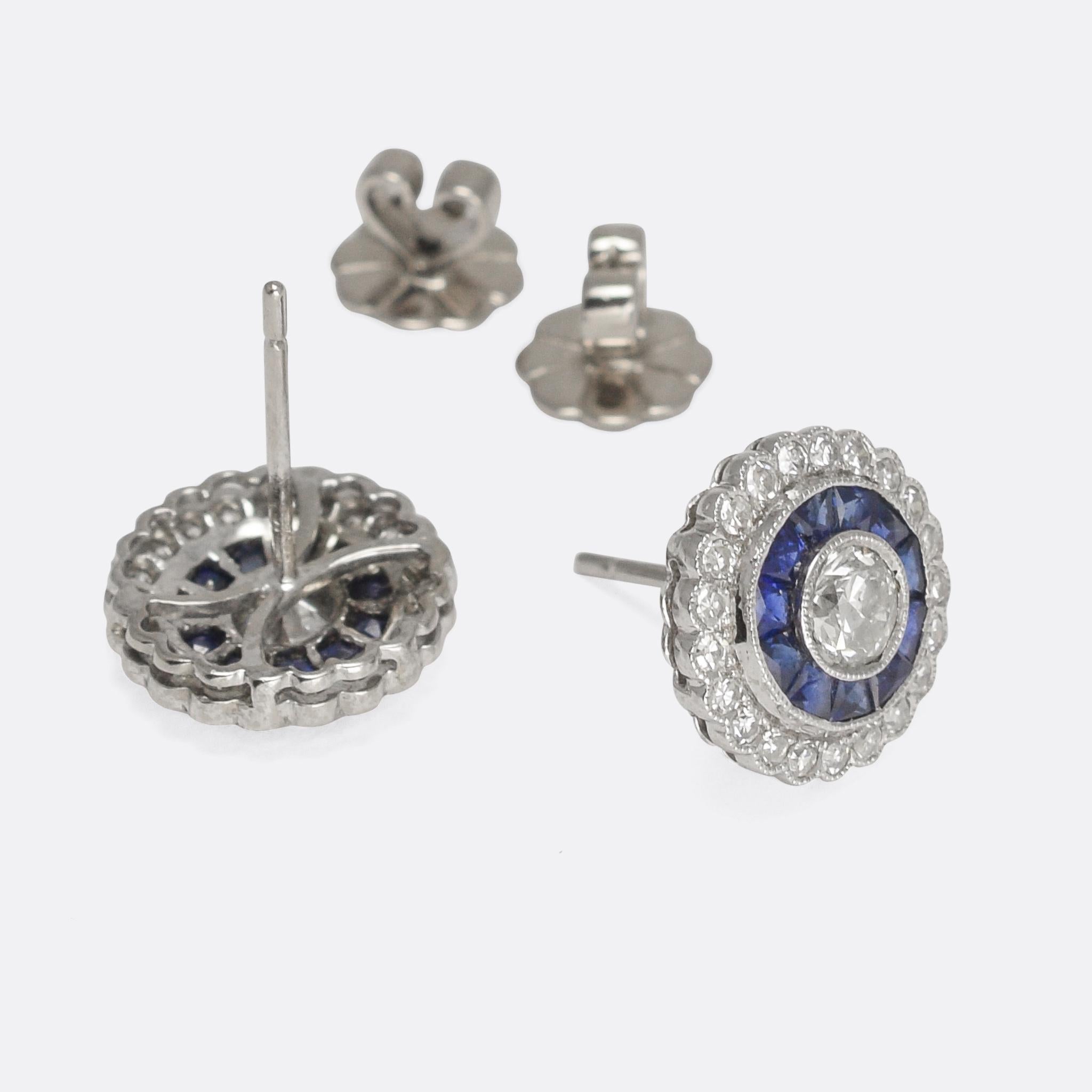 A stunning pair of Art Deco target earrings modelled dating from the 1920s. They're modelled in platinum throughout and set with white diamonds and blue sapphires. The central stones are bright brilliant cuts - .33 carats each - surrounded by a halo