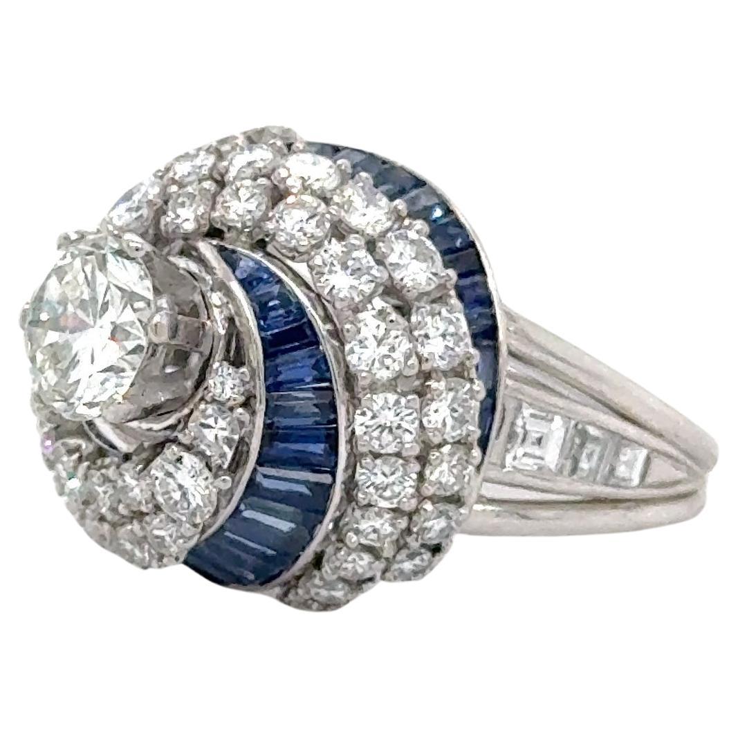 Amazing design seen on this Art Deco treasure. This beautiful ring is crafted in platinum and showcases both natural blue sapphire and diamond gemstones. The focal point of the ring is one round brilliant cut diamond measuring 6.55 x 6.6 mm with an