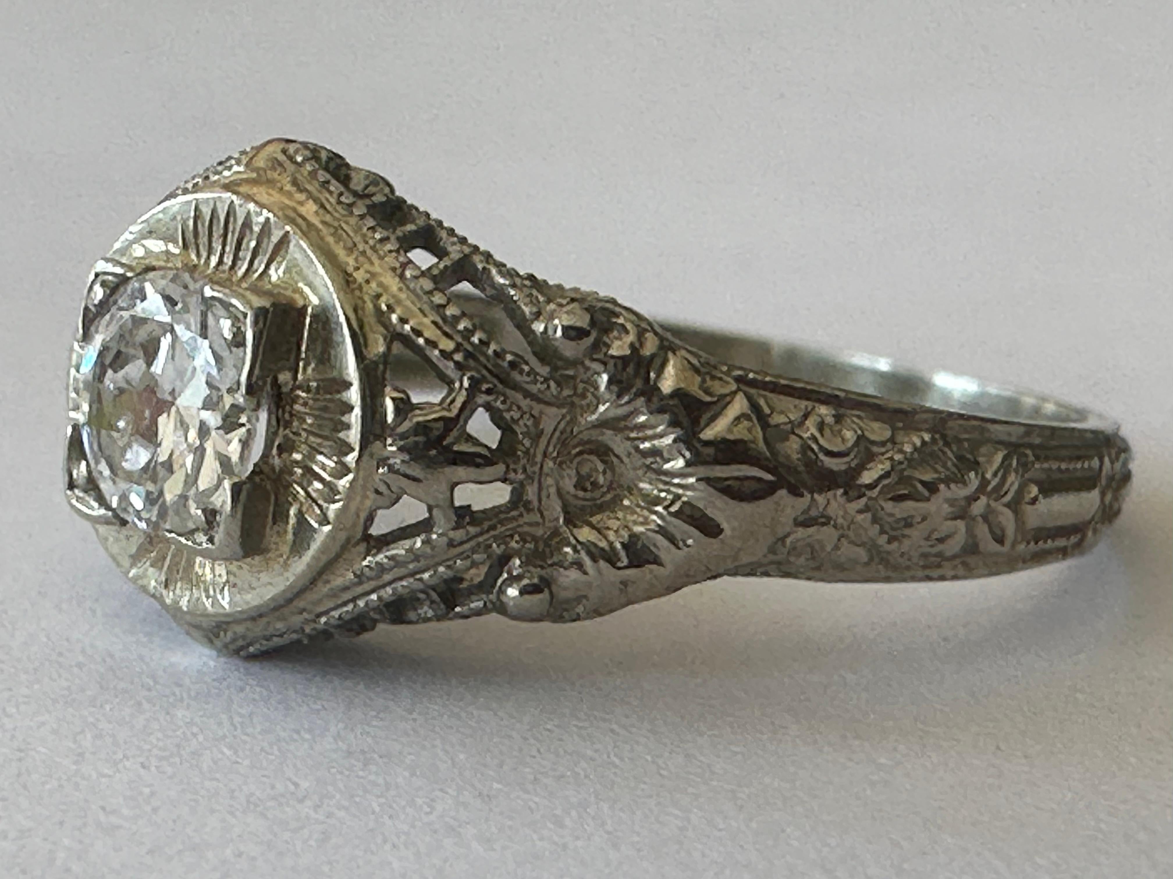 An Old European-cut diamond measuring approximately 0.30 carat, F color VS clarity, shines at the center of this late Art Deco gem atop a fanciful filigree mounting and a finely engraved shank. Set in 18K white gold. Circa 1940. 
