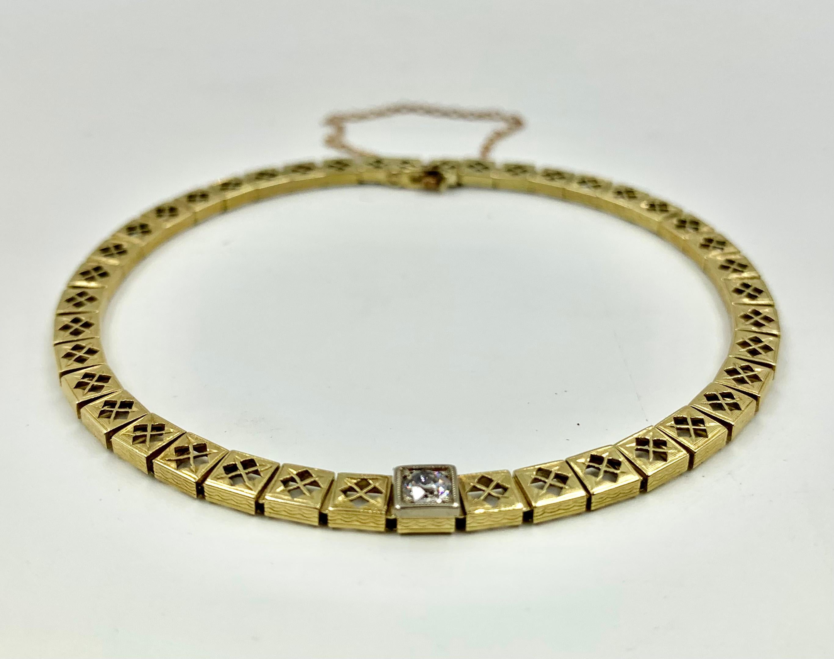 Unusual crossed arrow motif filigree gold bracelet with a central diamond solitaire.
Circa 1920
Composed of closely connected square filigree links, each with a pair of crossed arrows. The center of the bracelet with a classic solitaire diamond set