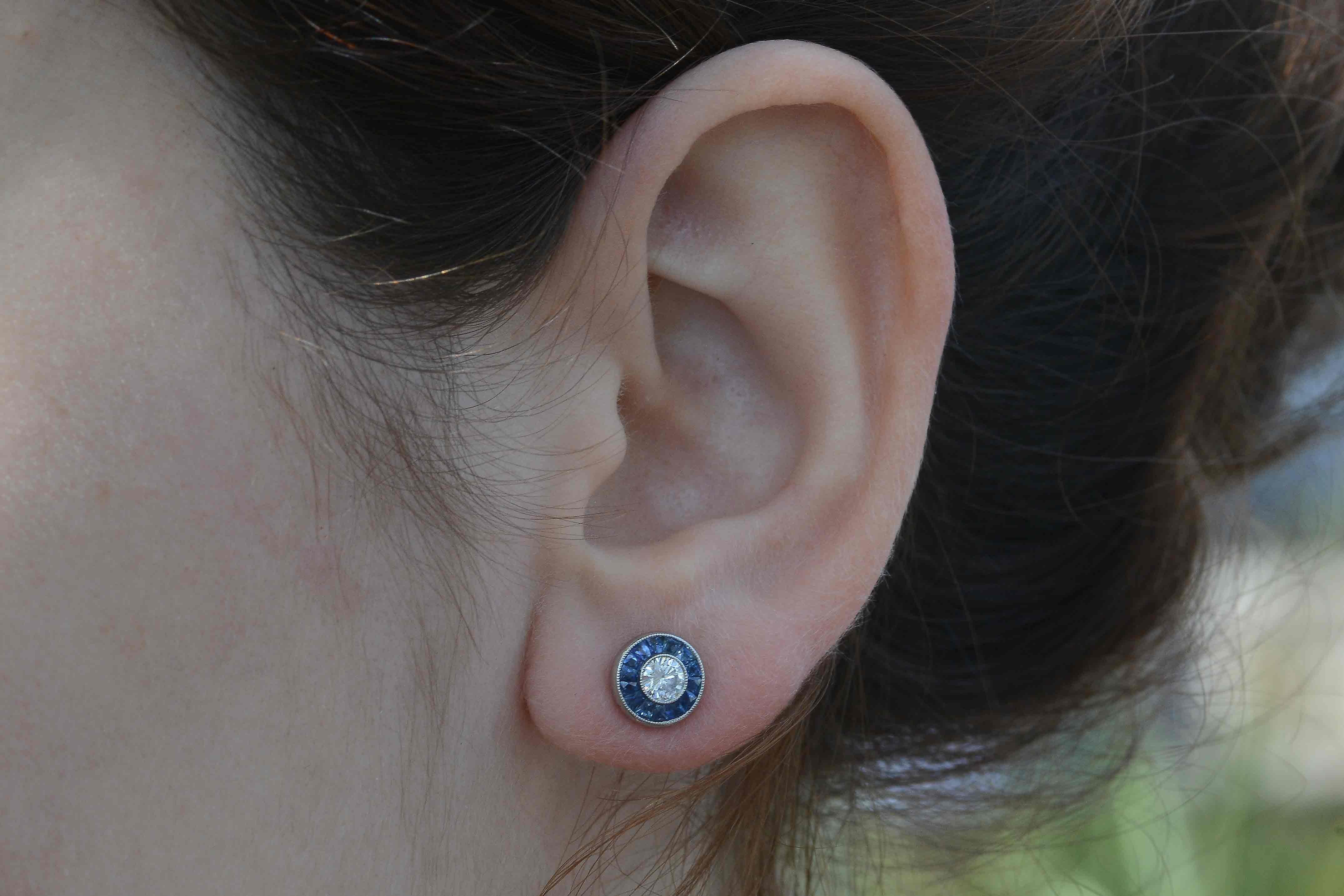 The sizzling, 1/2 carat total weight round diamonds really sparkle and dance accompanied by a halo of velvety blue, natural sapphires. Called a target design due to the resemblance of a bull's eye, highlighted by French cut (calibre') sapphires